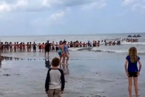 En el video se ve una larga cadena humana formada desde la orilla de la playa que penetra en un mar picado con unos bañistas a la cabeza llevando un flotador. Foto: captura de internet.