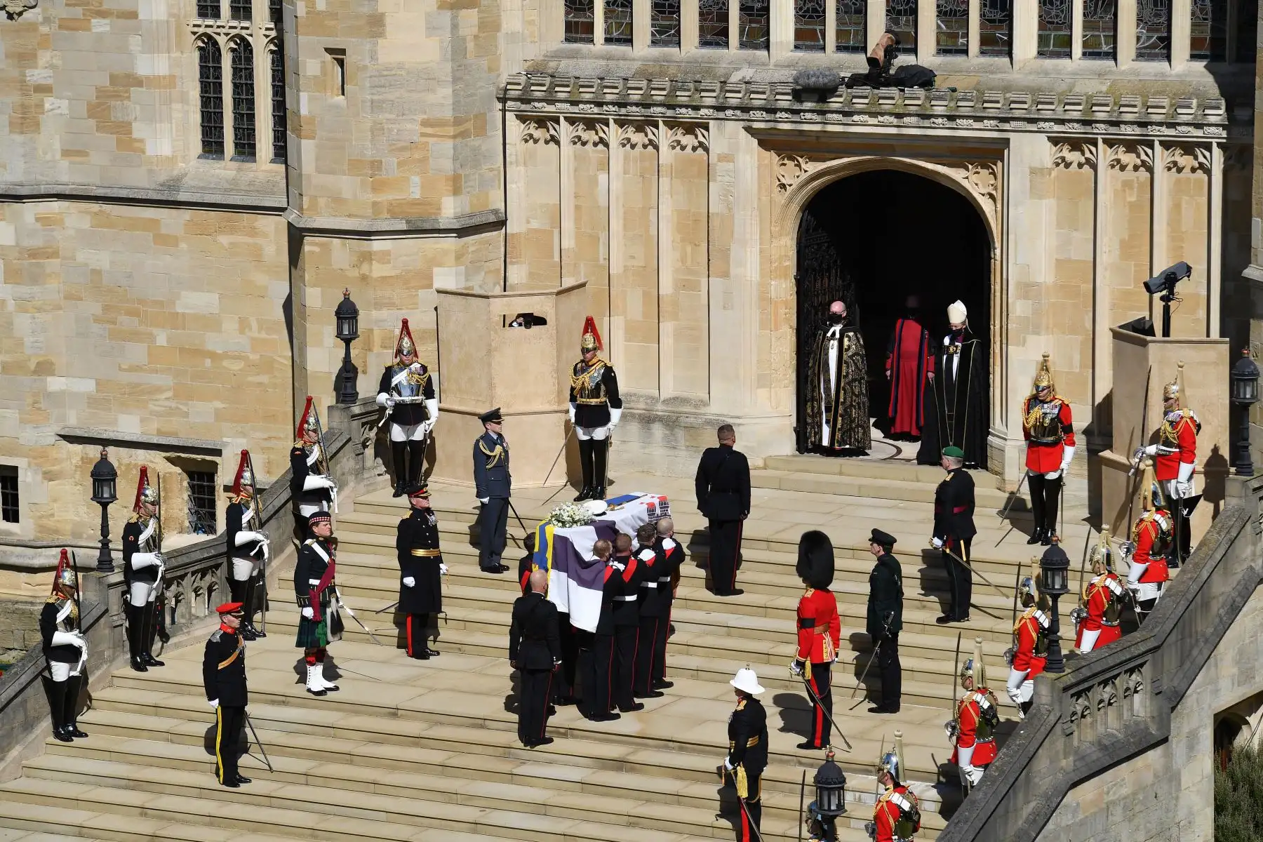 Los portadores del féretro de los Royal Marines que llevan el ataúd y los miembros de las fuerzas armadas hacen una pausa de un minuto de silencio en los escalones occidentales de la Capilla de San Jorge para marcar el inicio del funeral del príncipe Felipe de Gran Bretaña, duque de Edimburgo.
Foto: AFP