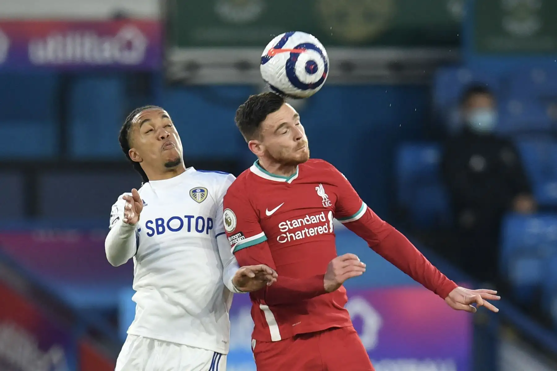 El centrocampista portugués del Leeds United Helder Costa salta junto a defensor escocés del Liverpool Andrew Robertson durante el partido de fútbol de la Premier League. Foto: AFP