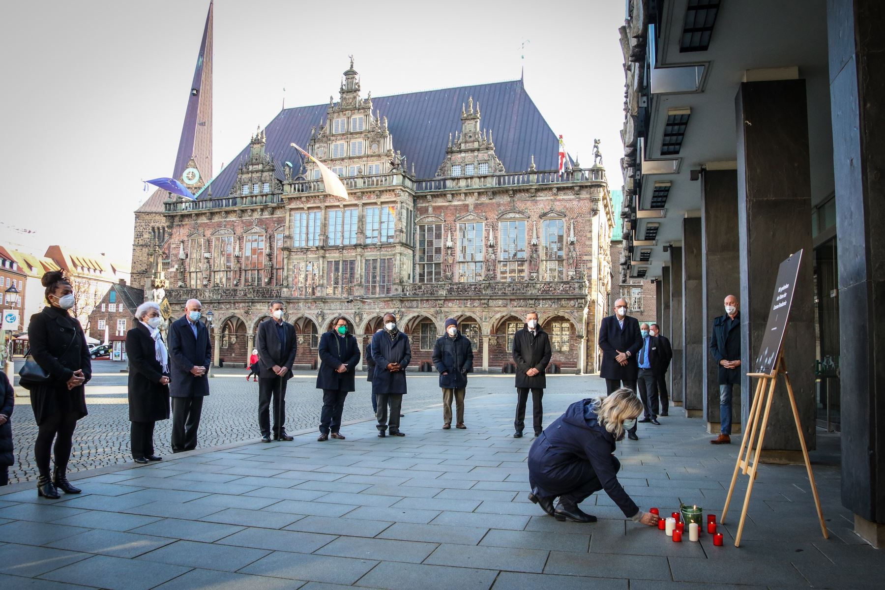 Una mujer coloca una vela durante una ceremonia para conmemorar las muertes por la pandemia de coronavirus frente al parlamento estatal de Bremen, norte de Alemania, el 18 de abril de 2021. Foto: EFE