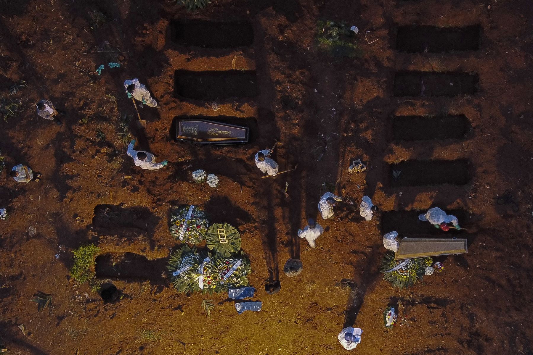 Vista aérea que muestra a trabajadores con equipo de protección como medida preventiva contra la COVID-19, entierran ataúdes en el cementerio de Vila Formosa en Sao Paulo, Brasil, el 17 de abril de 2021. Foto: AFP