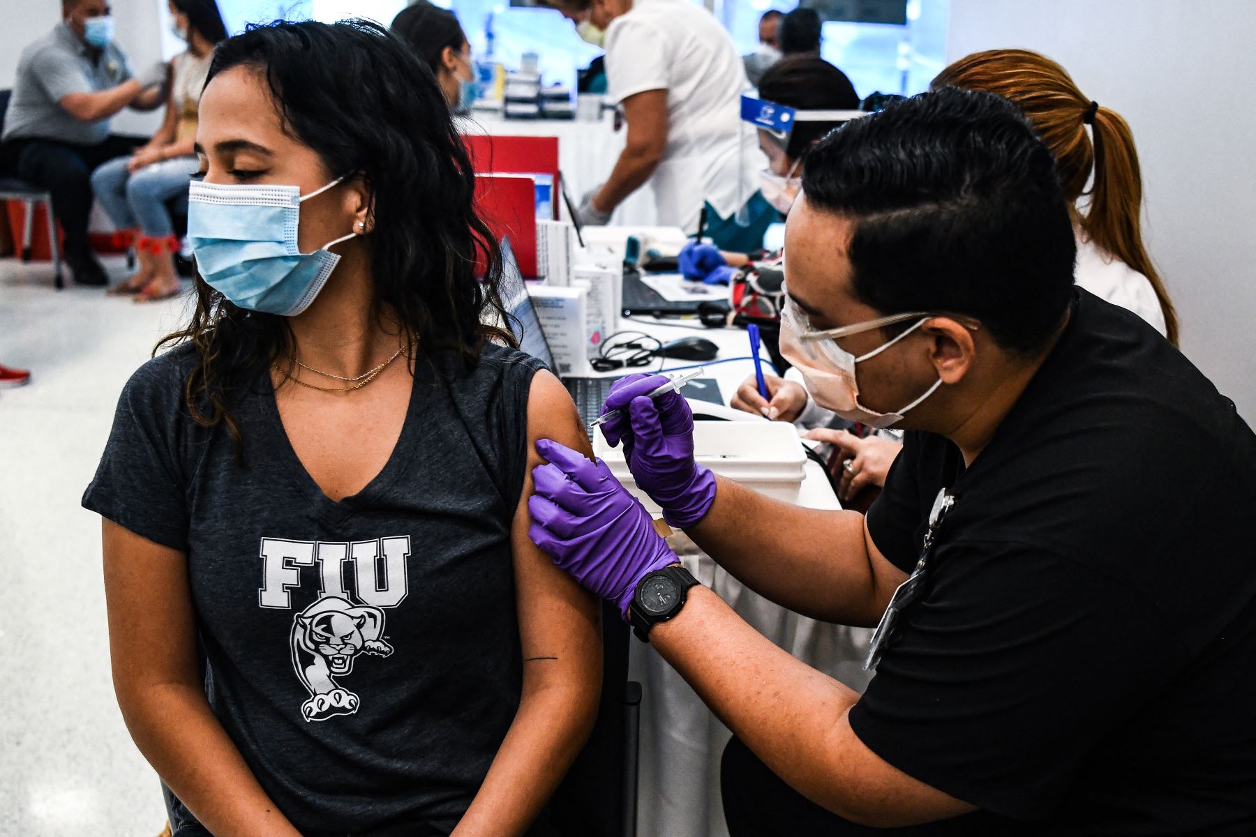 El estudiante de farmacia Jason Rodríguez administra una vacuna Covid-19 a la ciudadana boliviana Camila Gutiérrez en el Centro de Rehabilitación Christine E. Lynn en Miami, Florida el 15 de abril de 2021. Foto: AFP