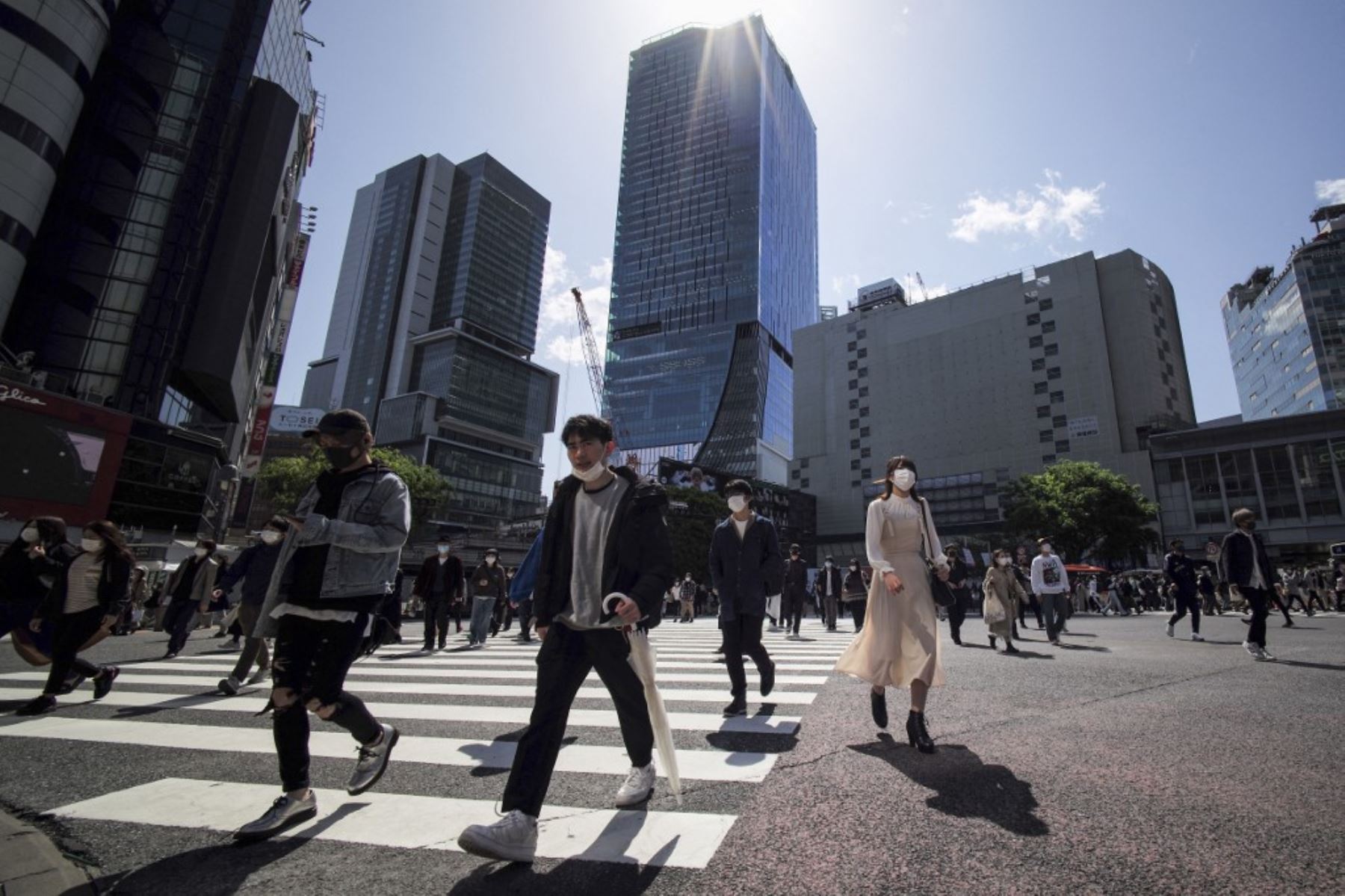 Los peatones con mascarillas caminan sobre el emblemático cruce de Shibuya en el distrito comercial y de entretenimiento de la zona en Tokio, bajo las medidas de cuasi-emergencia más recientes en medio de un aumento en los casos de coronavirus covid-19 en el país. Foto: AFP