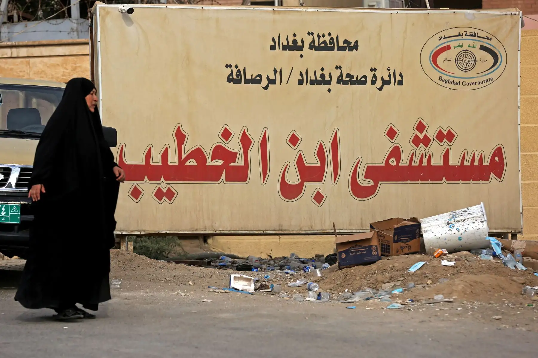 Una mujer iraquí pasa junto a una valla publicitaria con el nombre del Hospital Ibn Al-Khatib en Bagdad, después de que estallara un incendio en el centro médico reservado para los casos más graves de covid-19. 
Foto: AFP