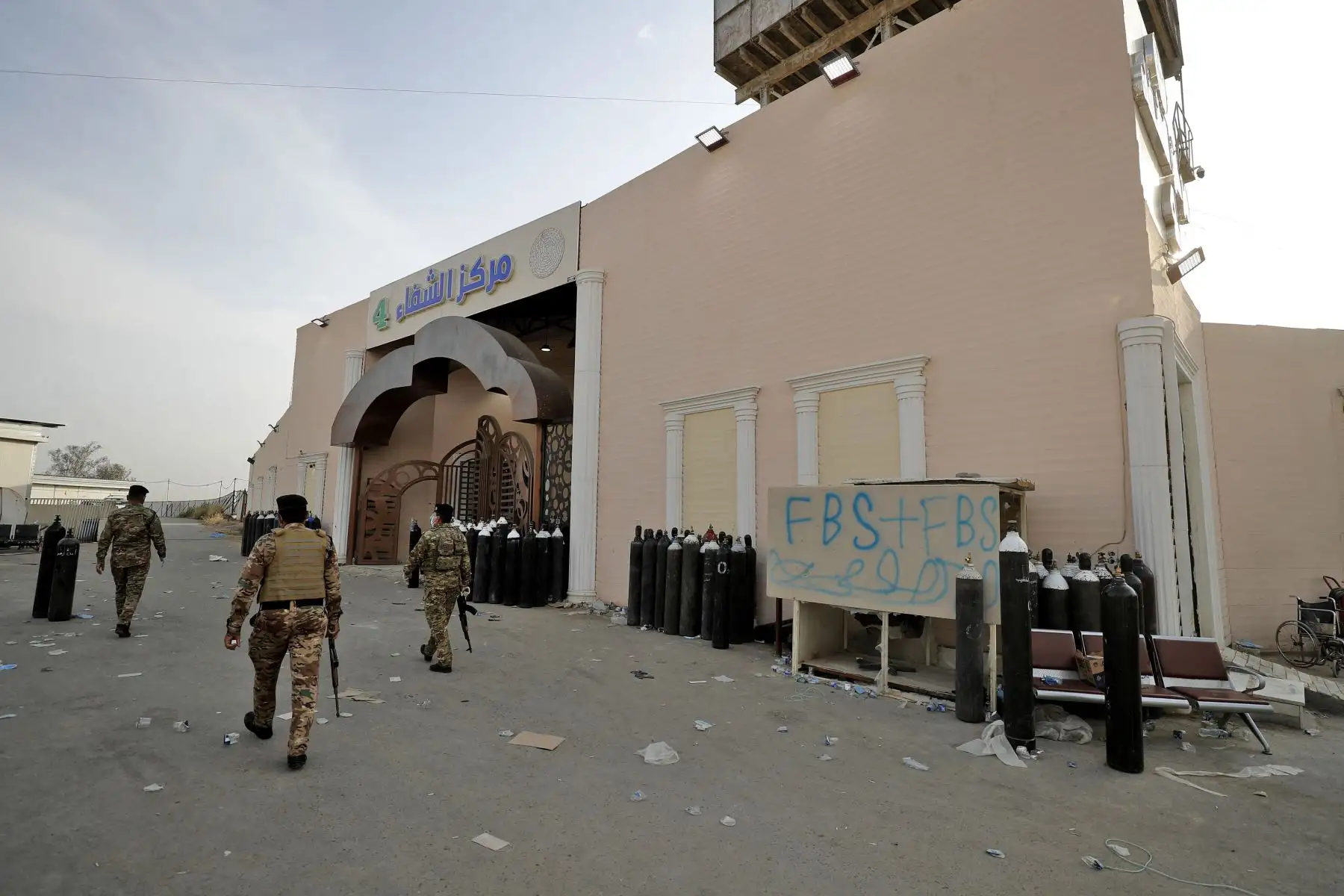 Miembros de las fuerzas de seguridad iraquíes se encuentran en la puerta del Hospital Ibn Al-Khatib en Bagdad, después de que estallara un incendio en la instalación médica reservada para los casos más graves de covid-19. 
Foto: AFP