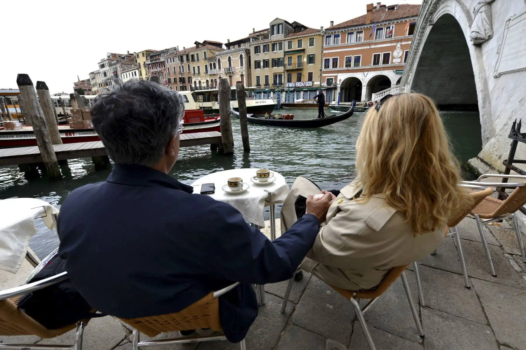 Una pareja toma un café en un bar junto al puente de Rialto en el centro de Venecia el 26 de abril de 2021. Foto: AFP