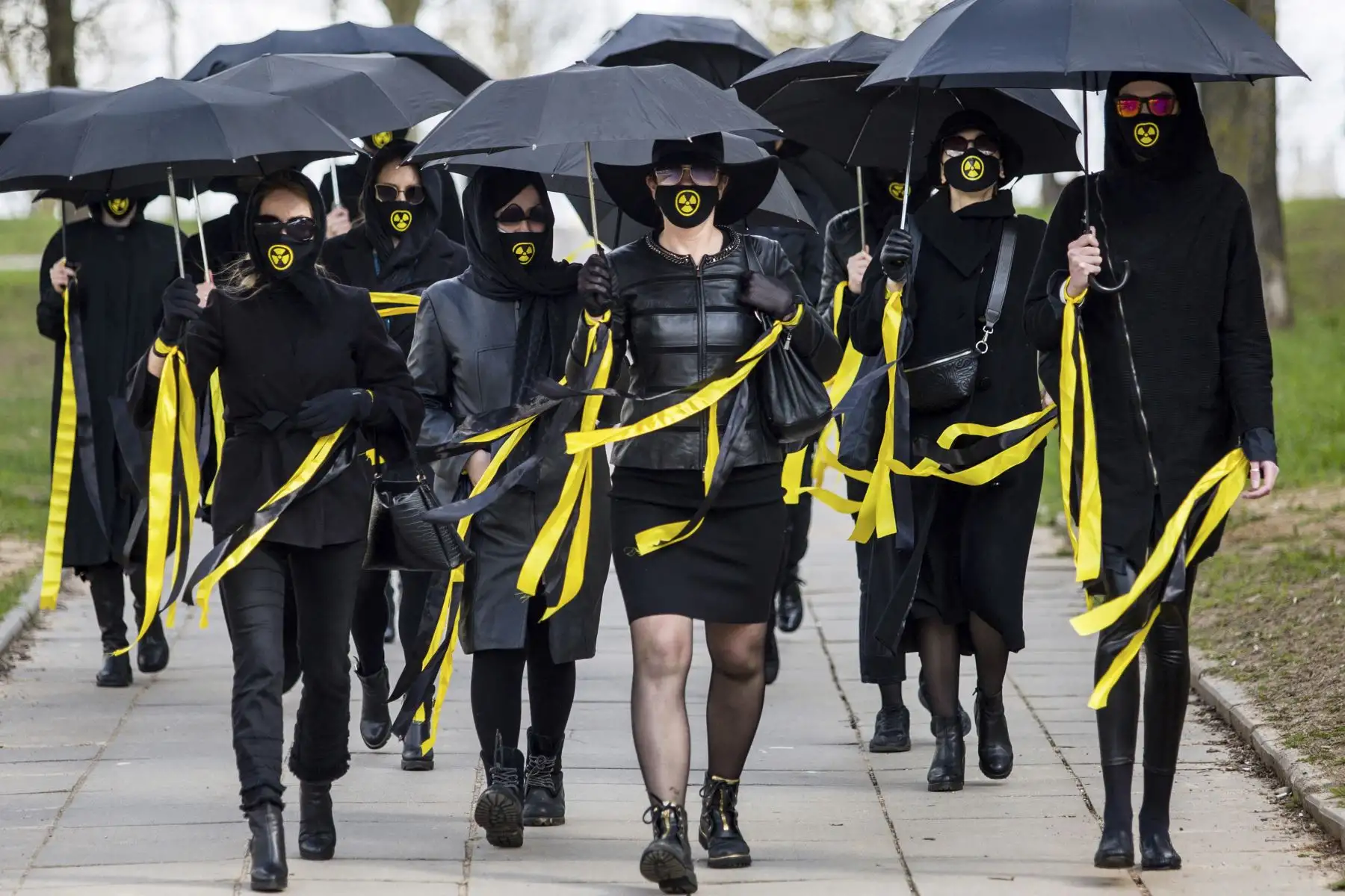 Mujeres vestidas con ropa negra y mascarillas con signo de radiactividad marchan bajo los paraguas en Minsk, el 26 de abril de 2021, para conmemorar a las víctimas del desastre nuclear de Chernobyl en el 35 aniversario de la tragedia. Foto: AFP