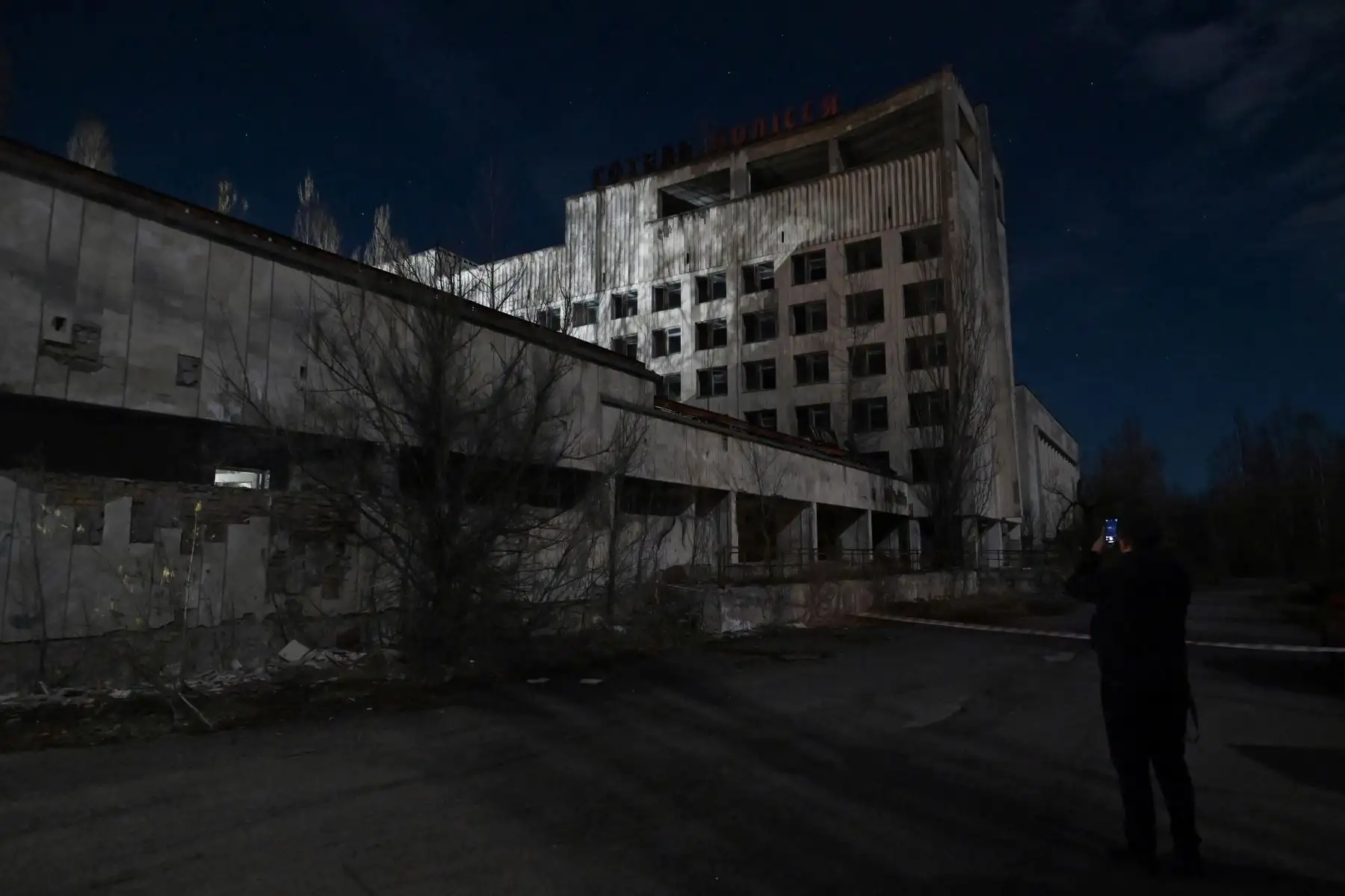 Un visitante toma una foto de un edificio abandonado en la ciudad fantasma de Pripyat, cerca de la planta de energía nuclear de Chernobyl, el 26 de abril de 2021, un evento para conmemorar el 35 aniversario del desastre nuclear. Foto: AFP