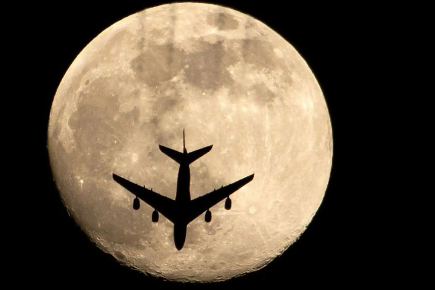 Un avión pasa frente a la luna ,  en la ciudad de Basora, en el sur de Irak.
Foto: AFP