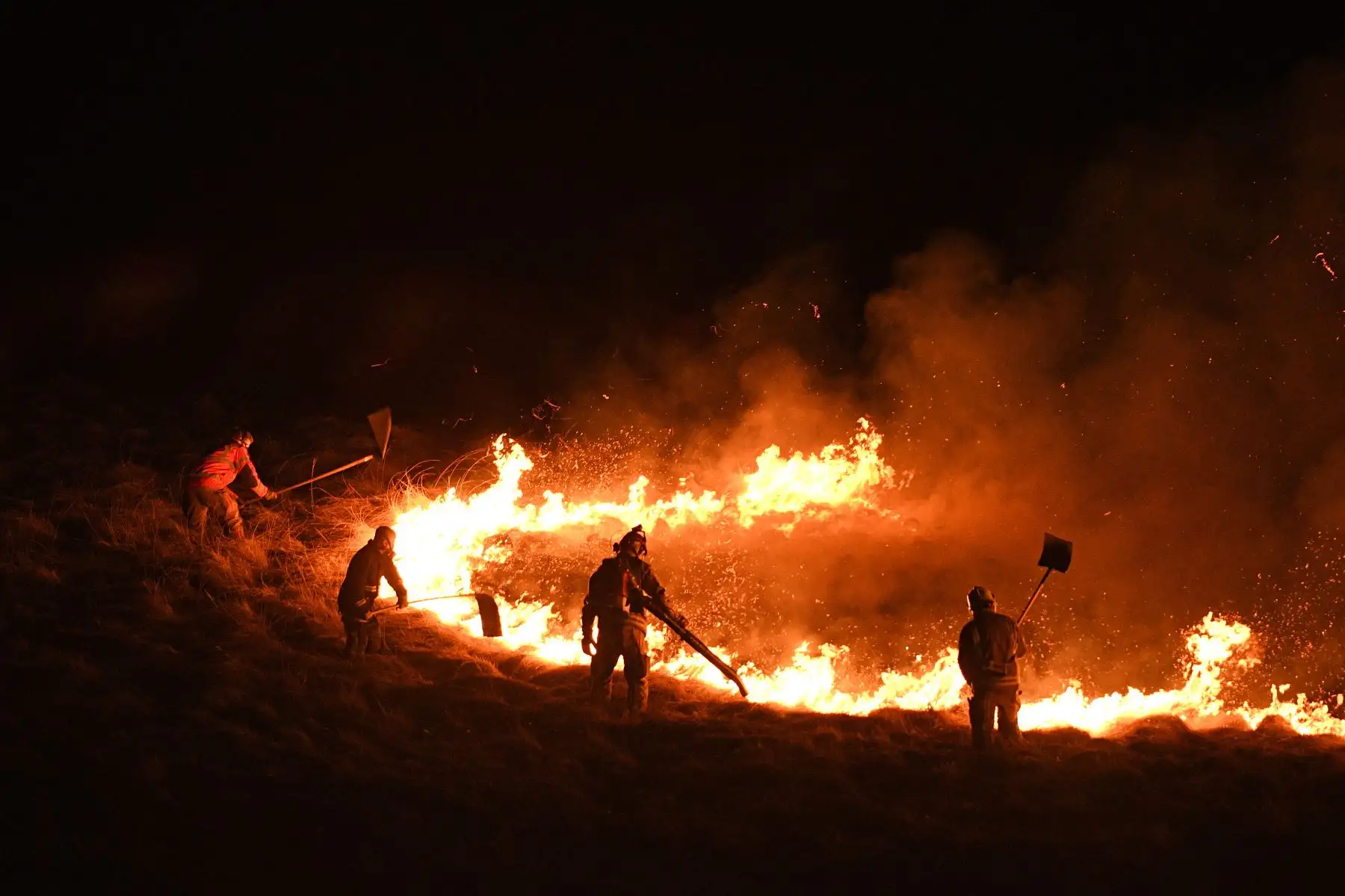 Los bomberos luchan por controlar las llamas de un incendio en el páramo Marsden, cerca de Huddersfield, en el norte de Inglaterra, el 25 de abril de 2021. Foto: AFP