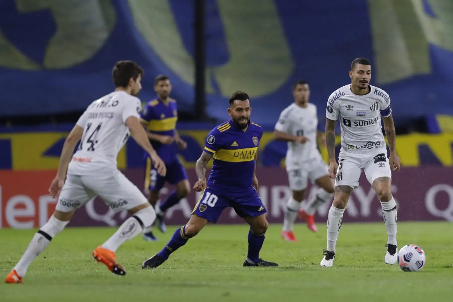 Los  brasileños  Luan Peres  y  Santos Alison del Santos FC compiten,por el balón, con el argentino del Boca Juniors Carlos Tevés durante el partido de la fase de grupos del torneo de fútbol Copa Libertadores. Foto: AFP