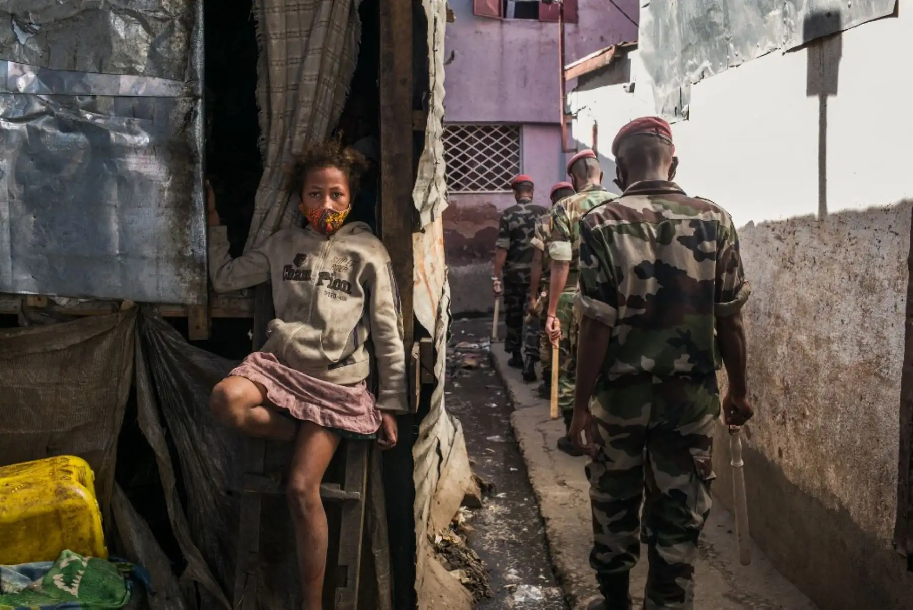 Una jovencita está sentada con su máscara protectora en la boca y la nariz mientras miembros del ejército patrullan las calles de Antananarivo ordenando a los ciudadanos que se vayan a casa mientras las autoridades malgaches declararon un cierre total de fin de semana en la capital para evitar la proliferación de covid-19. Foto: AFP