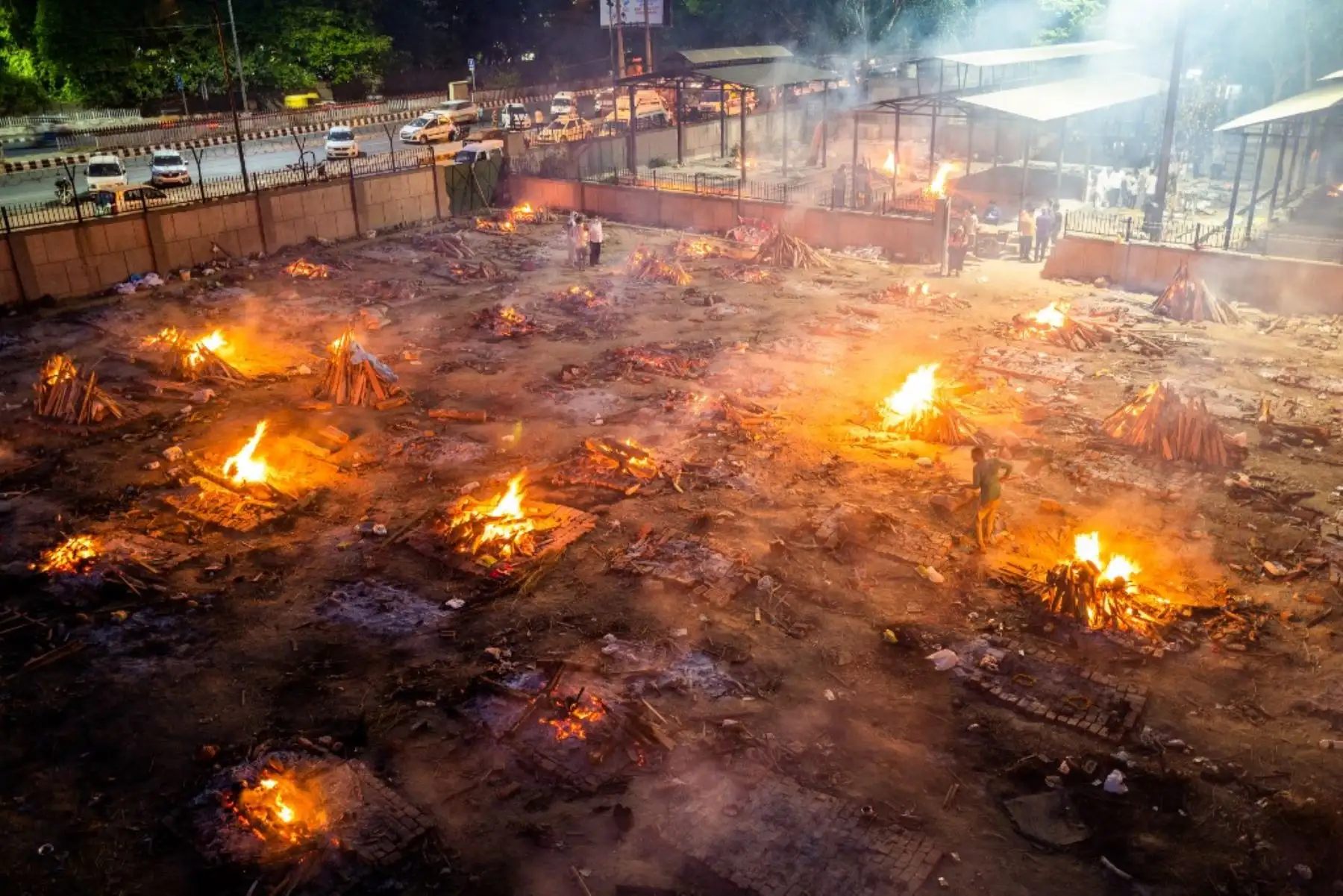 Se ven hombres alrededor de las piras ardientes de las víctimas que perdieron la vida debido al coronavirus covid-19 en un campo de cremación en Nueva Delhi. Foto: AFP