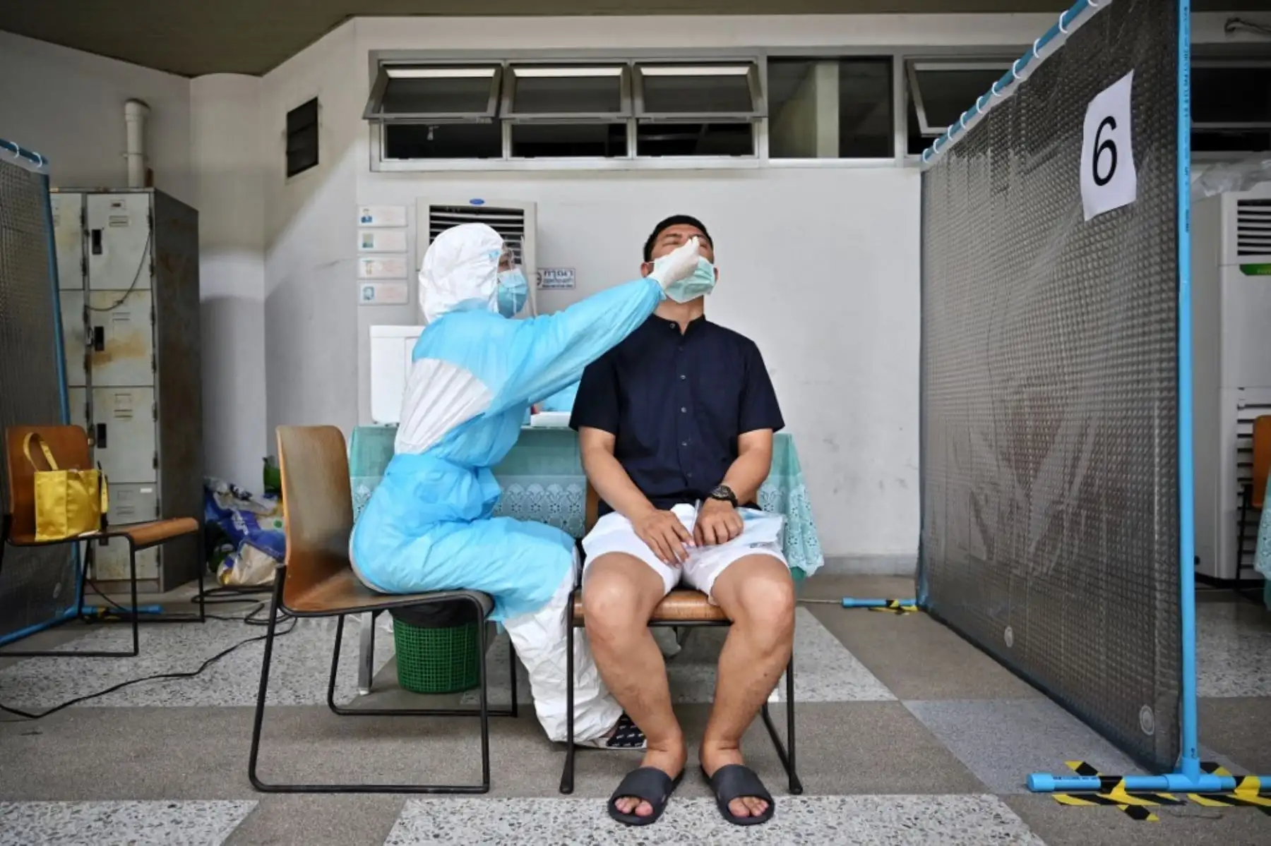 Un trabajador médico que usa equipo de protección personal (EPP) toma una muestra de un hisopo nasal de un hombre para realizar una prueba del coronavirus covid-19 en el Estadio Tailandés-Japonés, también conocido como Centro Juvenil de Bangkok, en Bangkok. Foto: AFP