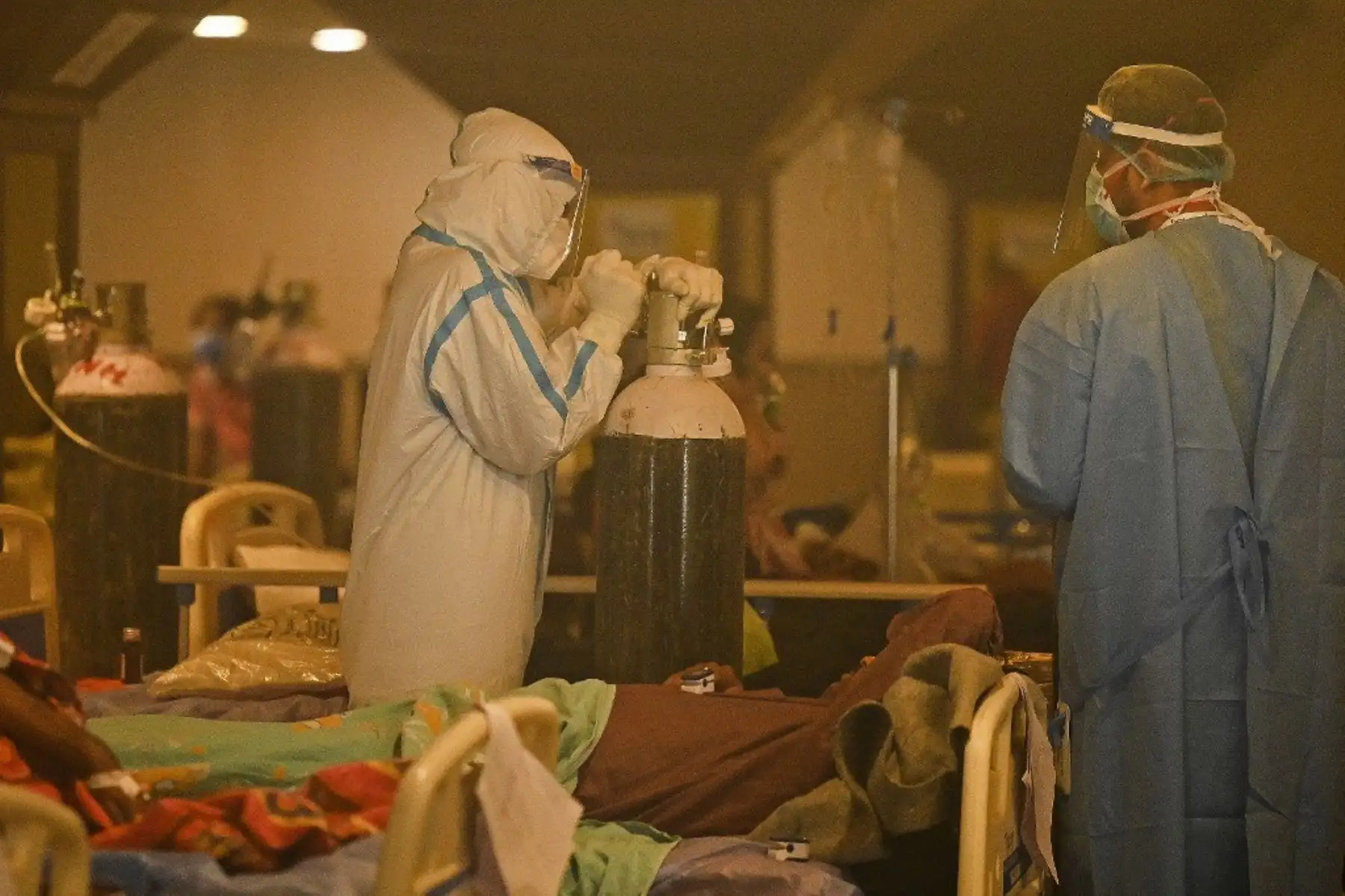 Trabajadores de salud, que usan equipo de protección personal (EPP), atienden a pacientes positivos para el coronavirus covid-19 dentro de un salón de banquetes convertido temporalmente en un centro de atención de covid en Nueva Delhi el 28 de abril de 2021. Foto: AFP