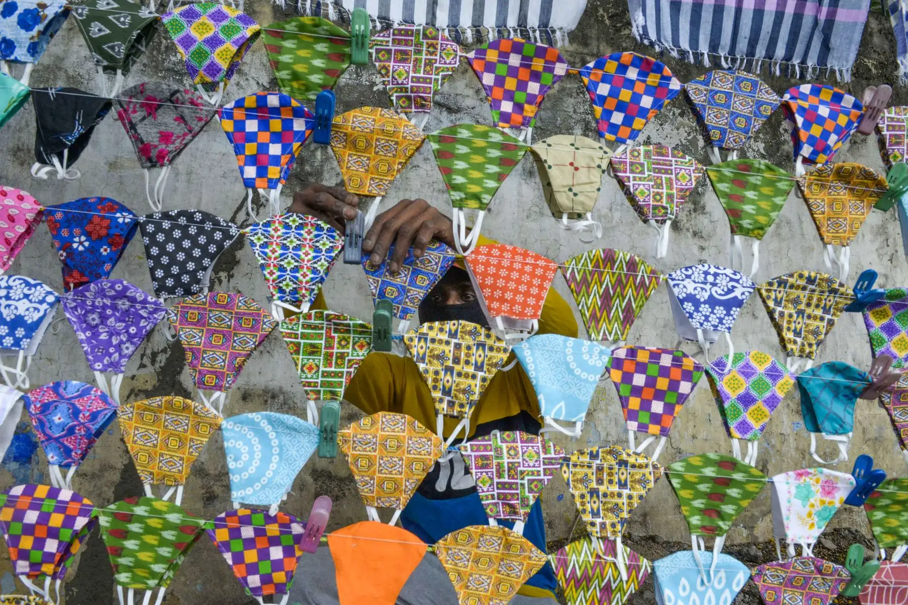 Un vendedor arregla mascarillas en su puesto a lo largo de una calle en medio de la pandemia del coronavirus Covid-19 en Hyderabad, India. Foto: AFP