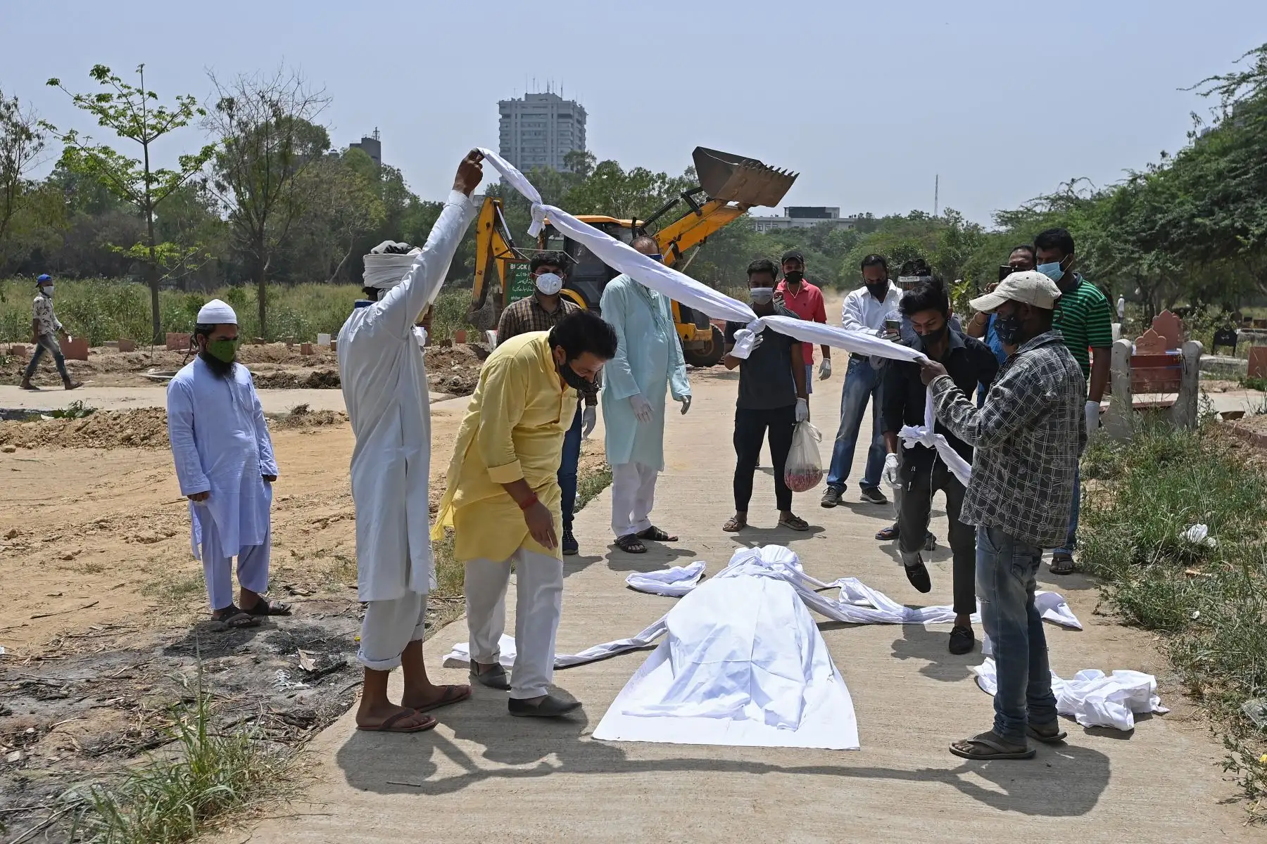 Familiares, amigos y trabajadores del cementerio preparan el cuerpo de una víctima del coronavirus Covid-19 antes del entierro en un cementerio en Nueva Delhi, India. Foto: AFP