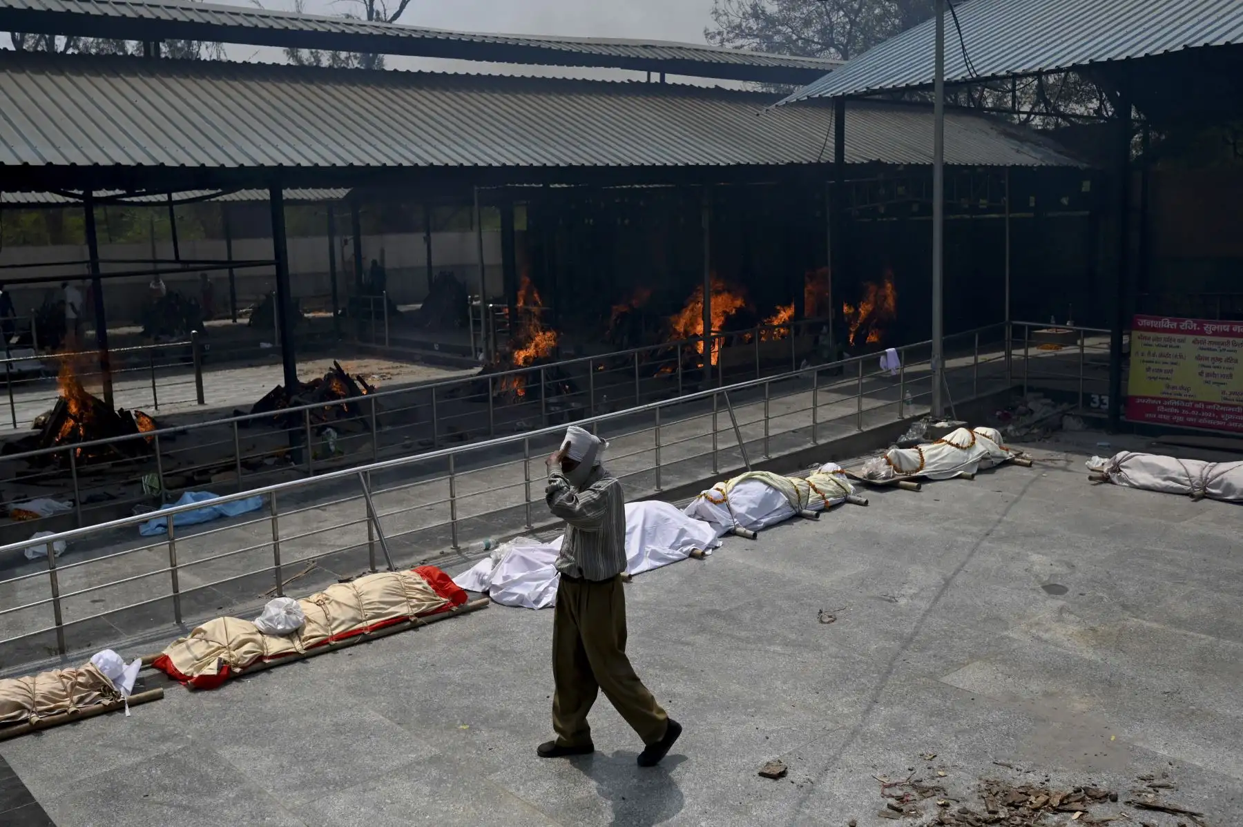 Un hombre pasa junto a los cuerpos de las víctimas del coronavirus Covid-19 alineadas antes de la cremación en un campo de cremación en Nueva Delhi, Indida. Foto: AFP