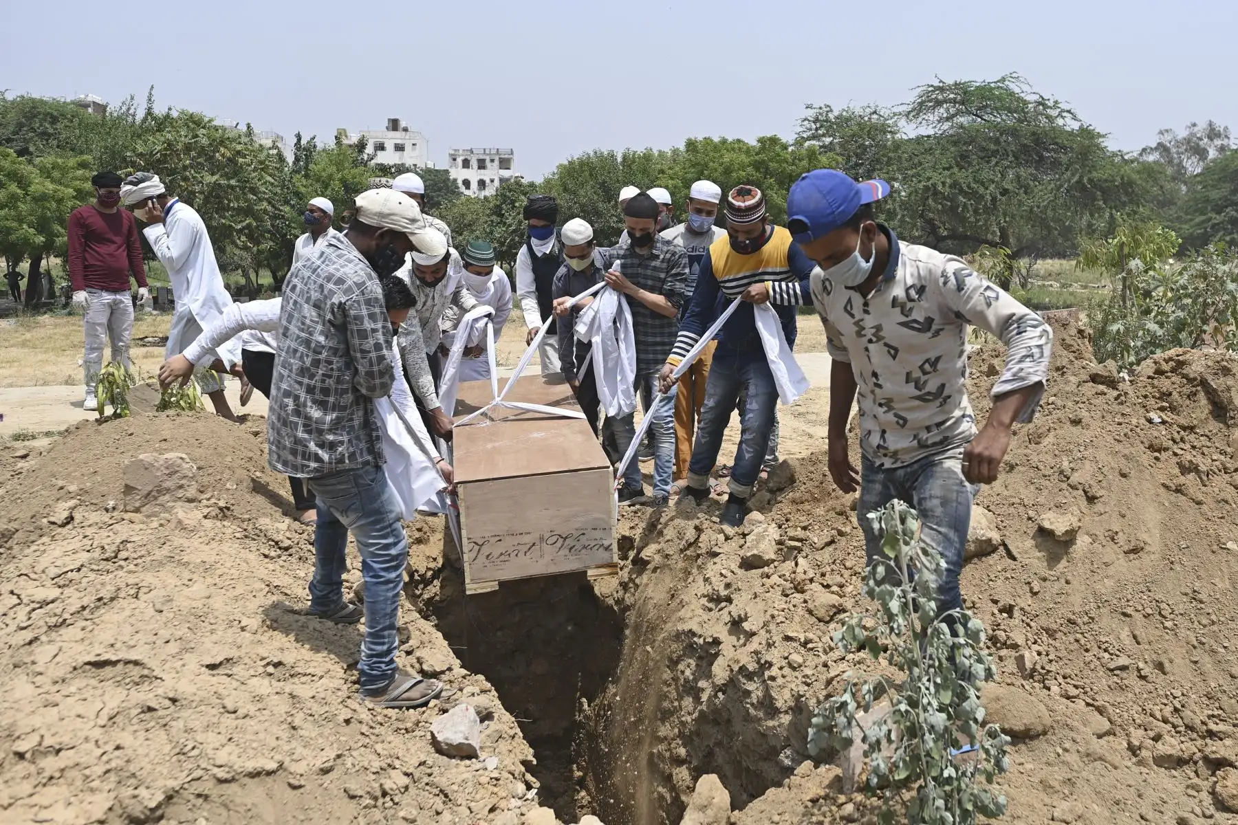 Familiares, amigos y trabajadores del cementerio se preparan para bajar el cuerpo de una víctima del coronavirus Covid-19 durante el entierro en un cementerio en Nueva Delhi. Foto: AFP