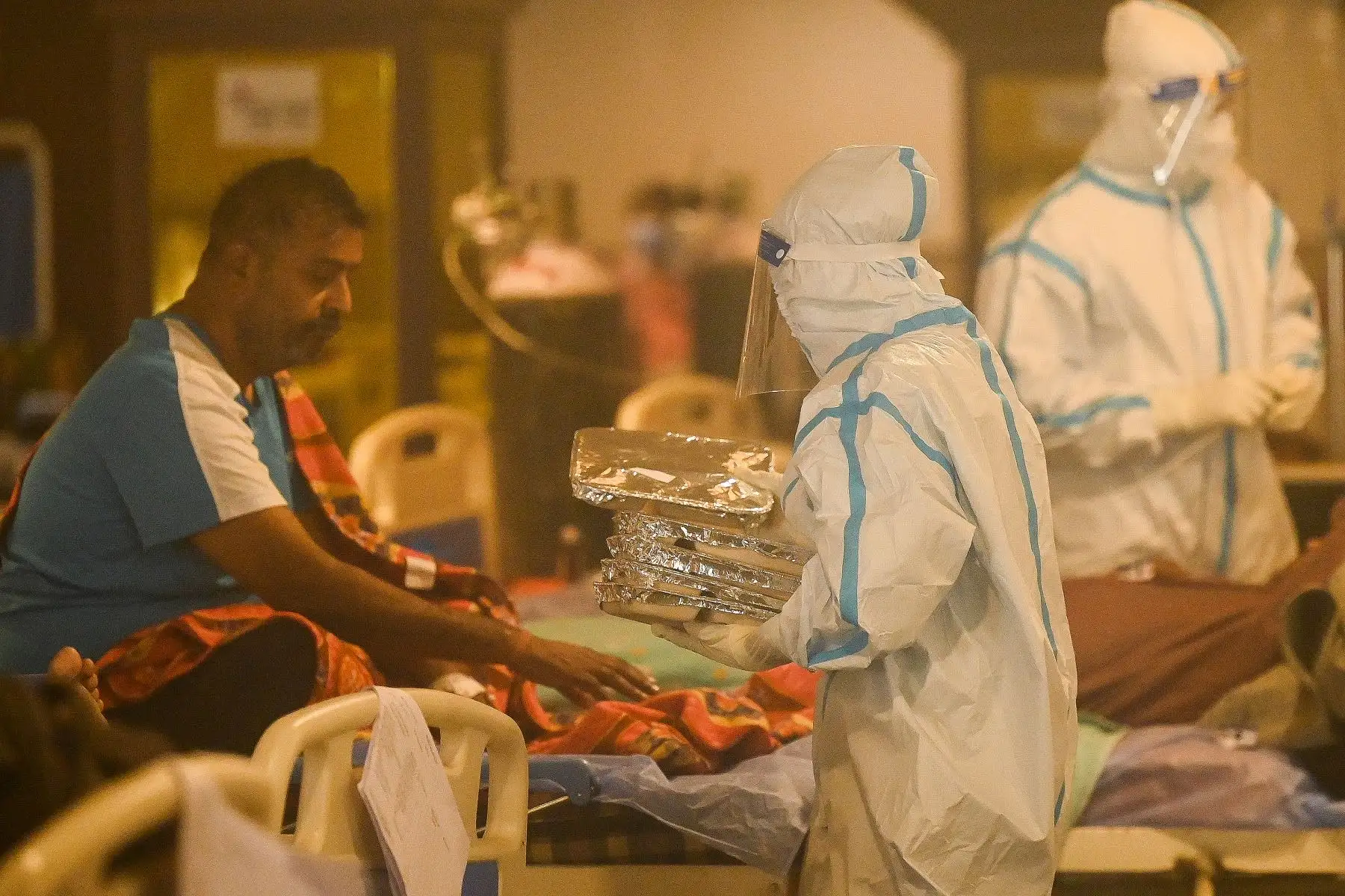Los trabajadores de la salud usan equipo de protección personal (EPP) para atender a pacientes positivos de coronavirus Covid-19 dentro de un salón convertido temporalmente en un centro de atención de covid en Nueva Delhi, India. Foto: AFP
