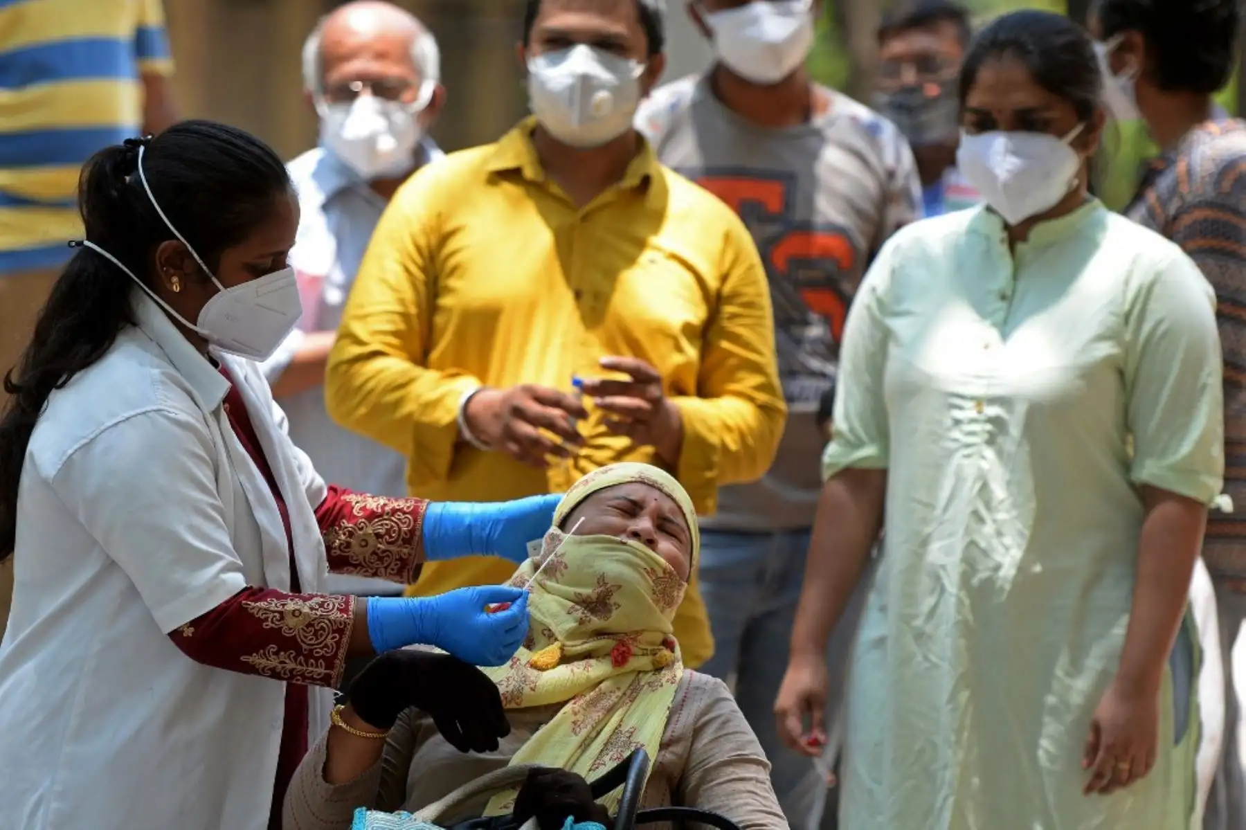 Un trabajador médico toma una muestra de hisopo de una mujer para una prueba de reacción en cadena de la polimerasa con transcripción inversa (RT-PCR) para la detección del coronavirus Covid-19 en un centro de pruebas en Hyderabad. Foto: AFP
