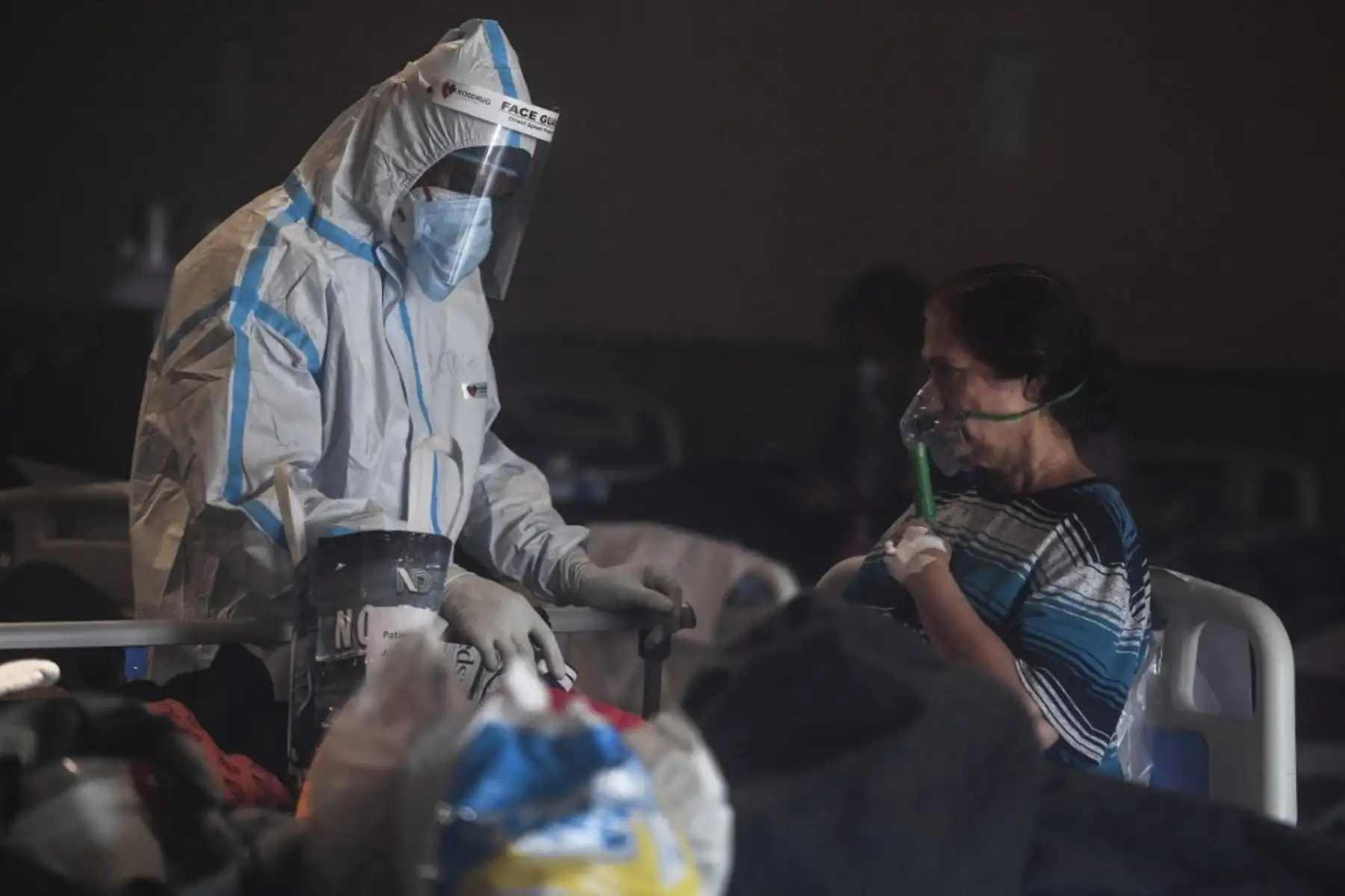Un trabajador de la salud que usa equipo de protección personal (EPP) atiende a un paciente con coronavirus covid-19 dentro de un salón de banquetes convertido temporalmente en un centro de atención de covid en Nueva Delhi. Foto: AFP