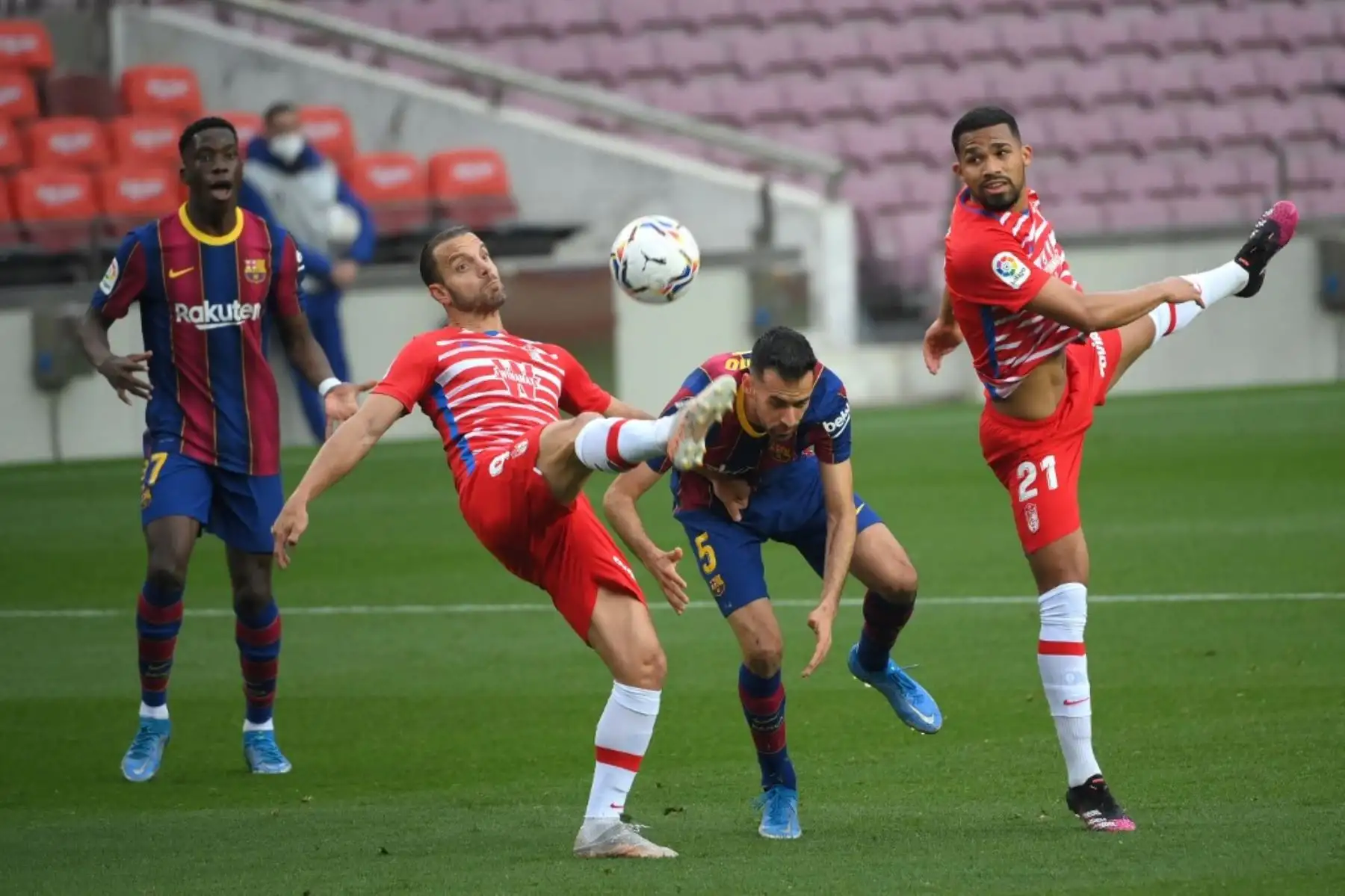 El delantero español del Granada Roberto Soldado (2R) y el centrocampista venezolano del Granada Yangel Herrera (R) desafían al centrocampista español del Barcelona Sergio Busquets delante del centrocampista español del Barcelona Ilaix Moriba (L) durante el partido de fútbol de la Liga española entre Barcelona y Granada en el estadio Camp Nou en Barcelona el 29 de abril de 2021. Foto: AFP