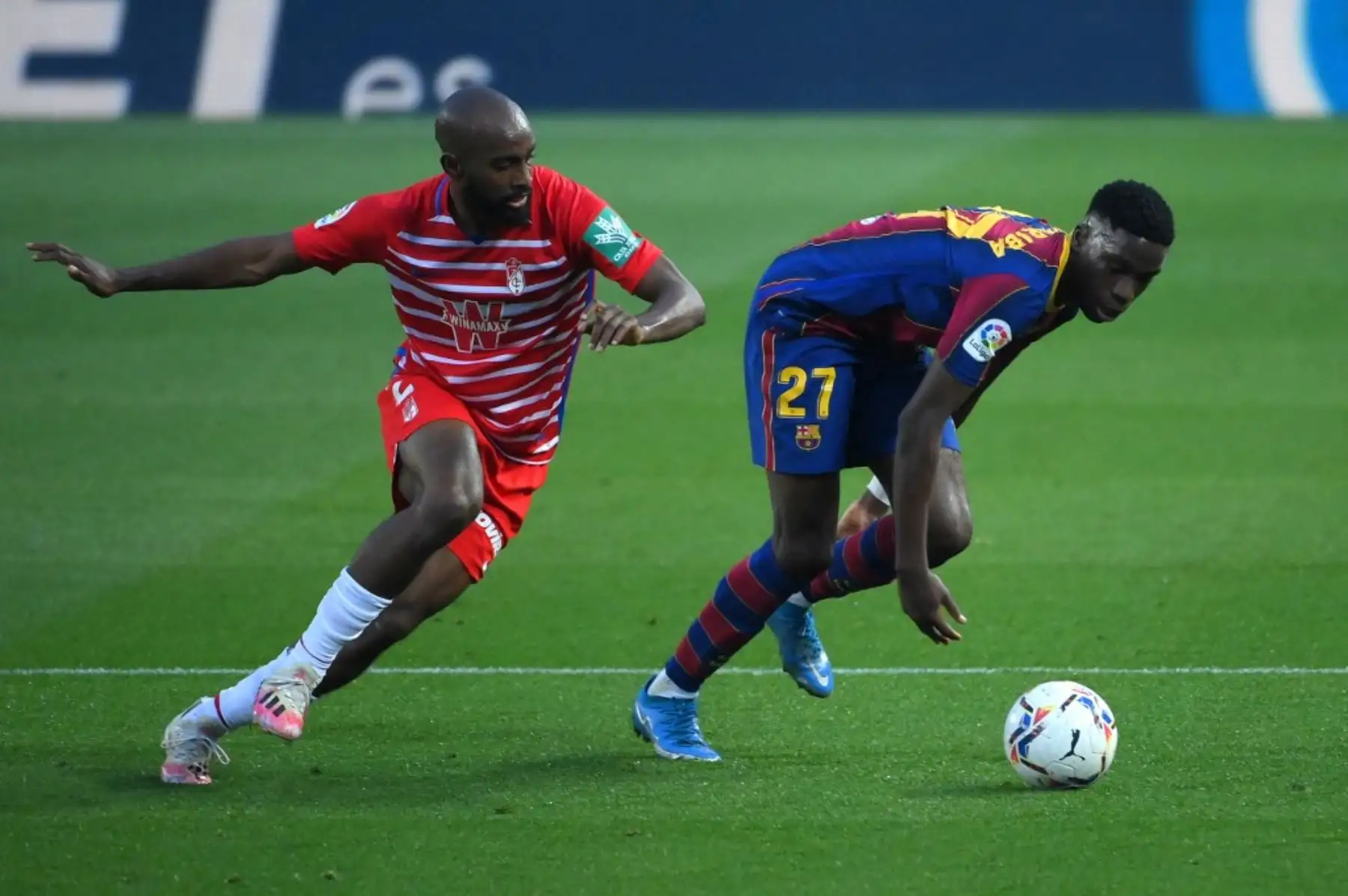 El defensa francés del Granada Dimitri Foulquier (L) y el centrocampista español del Barcelona Ilaix Moriba disputan el balón durante el partido de fútbol de la Liga española entre el Barcelona y el Granada en el estadio Camp Nou de Barcelona el 29 de abril de 2021. Foto: AFP