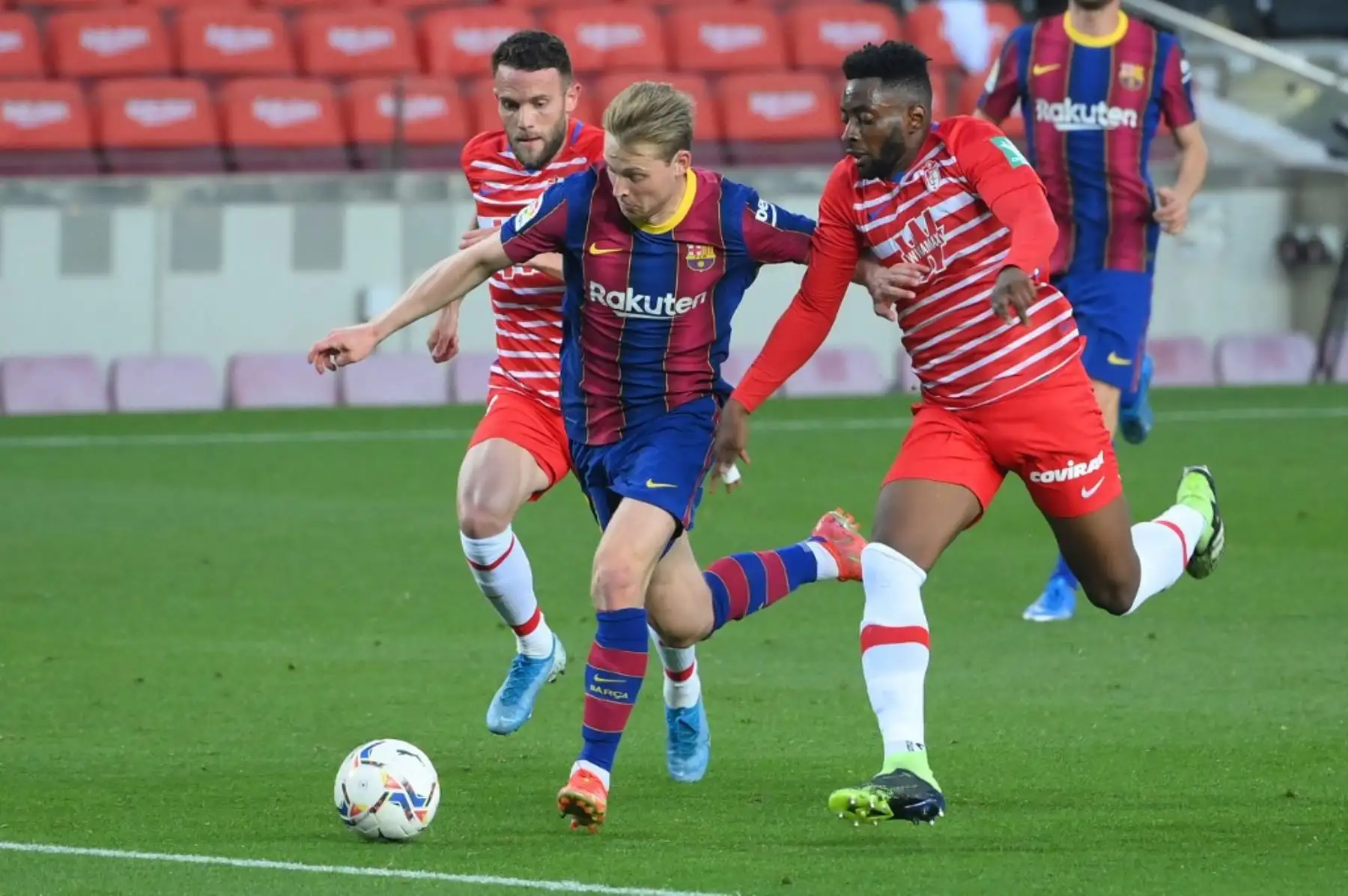El defensa español del Granada Quini (L) y el centrocampista camerunés del Granada Yan Brice Eteki (R) desafían al mediocampista holandés del Barcelona Frenkie De Jong durante el partido de fútbol de la Liga española entre Barcelona y Granada en el estadio Camp Nou de Barcelona el 29 de abril de 2021. Foto: AFP