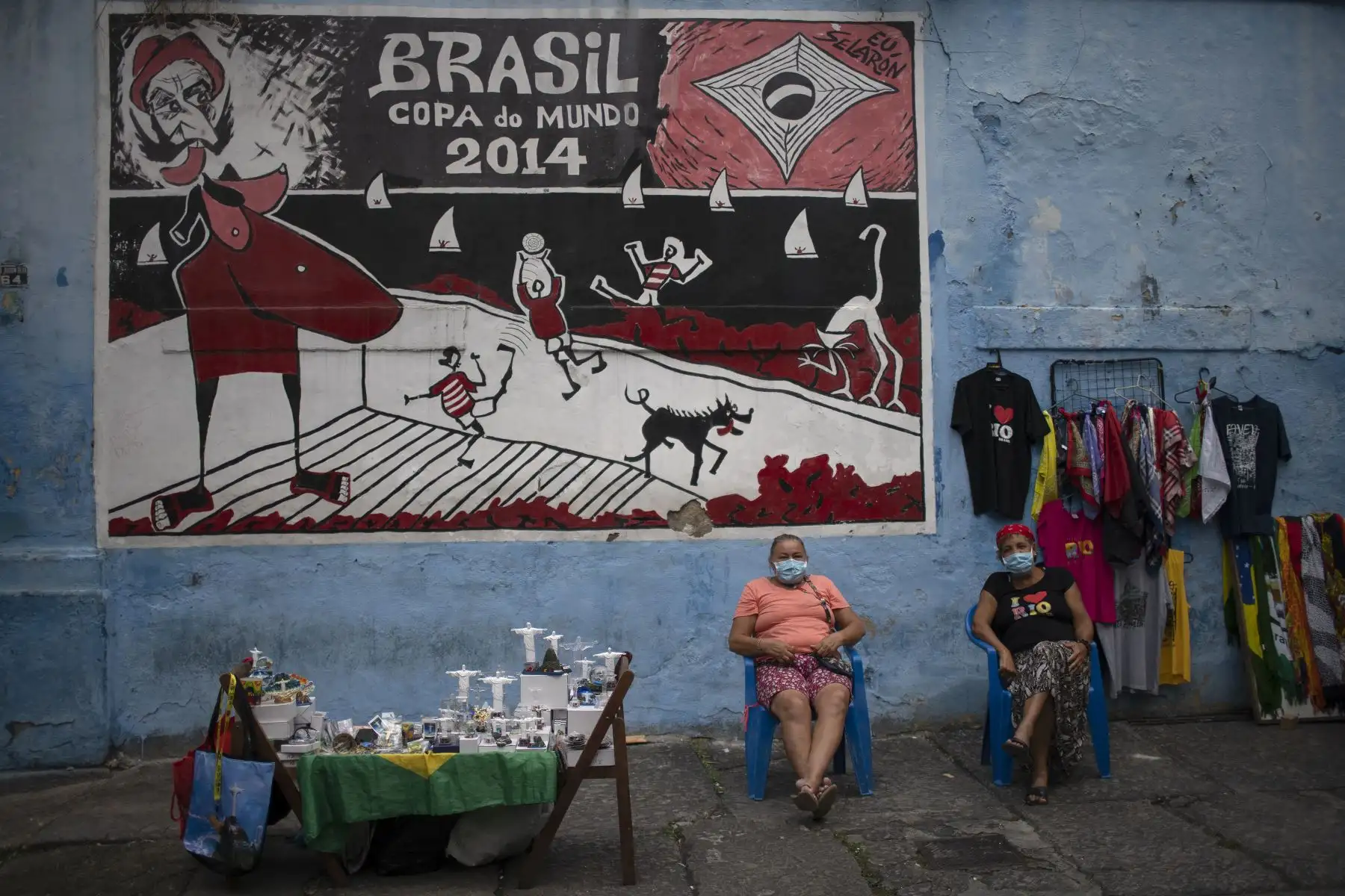 Vendedores ambulantes se sientan junto a miniaturas del Cristo Redentor frente a la escalera de Selaron, atracción turística de renombre internacional en el barrio Lapa, en Río de Janeiro, Brasil, el 29 de abril de 2021. Foto: AFP