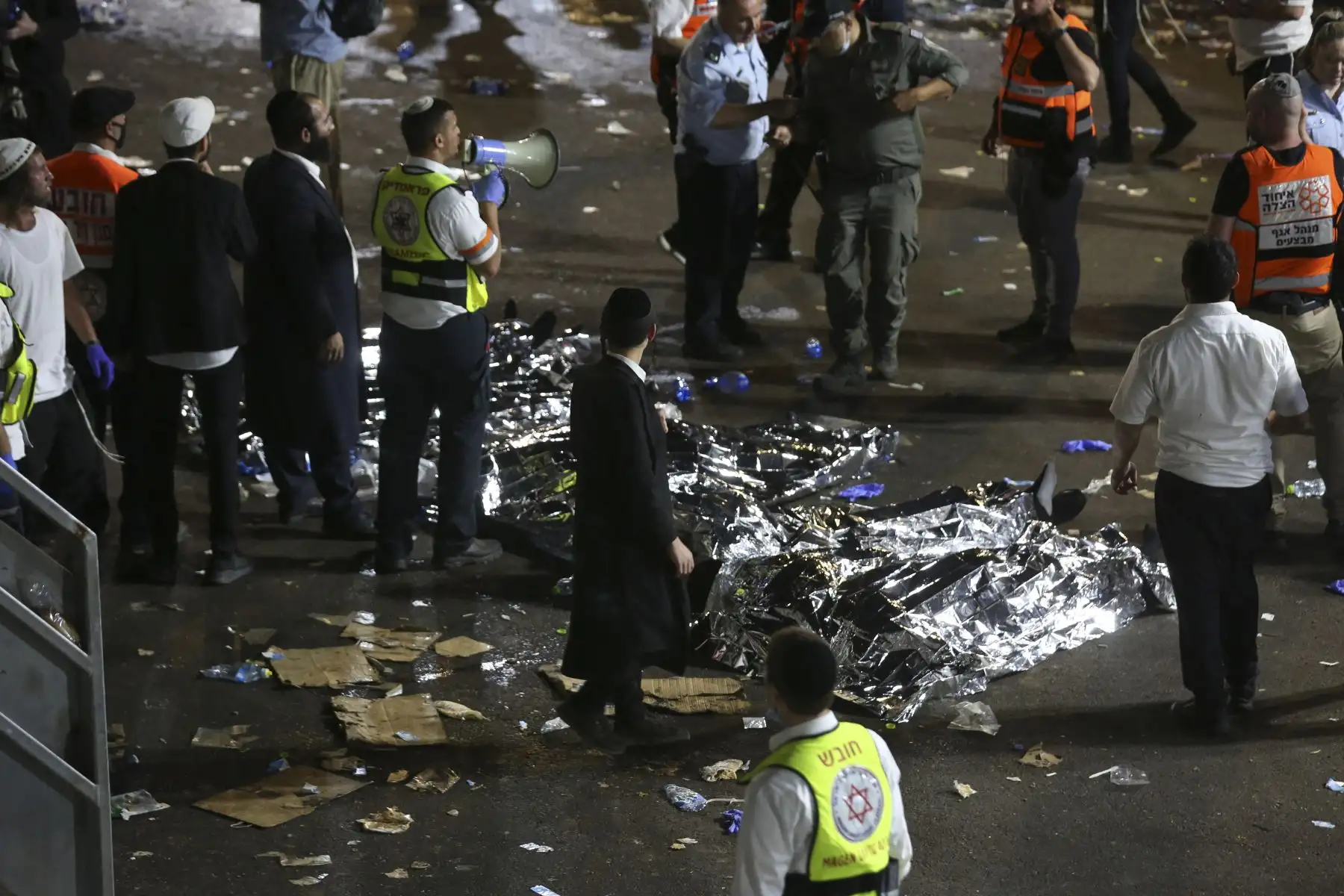 Hombres judíos ultraortodoxos se paran junto a cuerpos cubiertos después de que decenas de personas murieron y otras resultaron heridas después del colapso de una tribuna en Meron, Israel, donde decenas de miles de personas se reunieron para celebrar el festival de Lag Ba