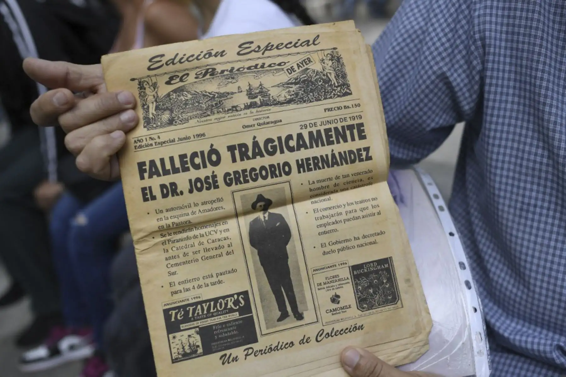 Un hombre sostiene una edición especial de un periódico relacionado con la muerte del médico venezolano José Gregorio Hernández, también llamado "el médico de los pobres", durante su ceremonia de beatificación frente a la iglesia La Candelaria en Caracas el 30 de abril de 2021. Foto: AFP