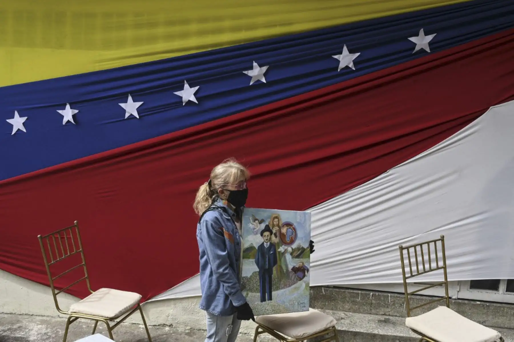 Un devoto del médico venezolano José Gregorio Hernández, también llamado "el médico de los pobres", se encuentra junto a un altar colocado en una calle del barrio La Pastora -donde vivía- en Caracas el 30 de abril de 2021. Foto: AFP