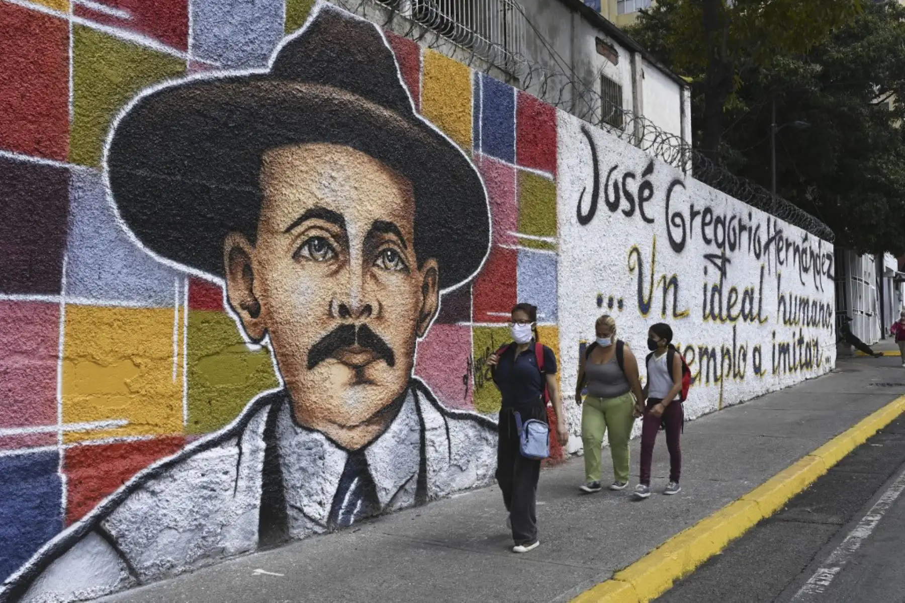 La gente pasa frente a un mural que representa al médico venezolano José Gregorio Hernández, también llamado "el médico de los pobres", en una calle del barrio La Pastora -donde vivía- en Caracas el 30 de abril de 2021. Foto: AFP