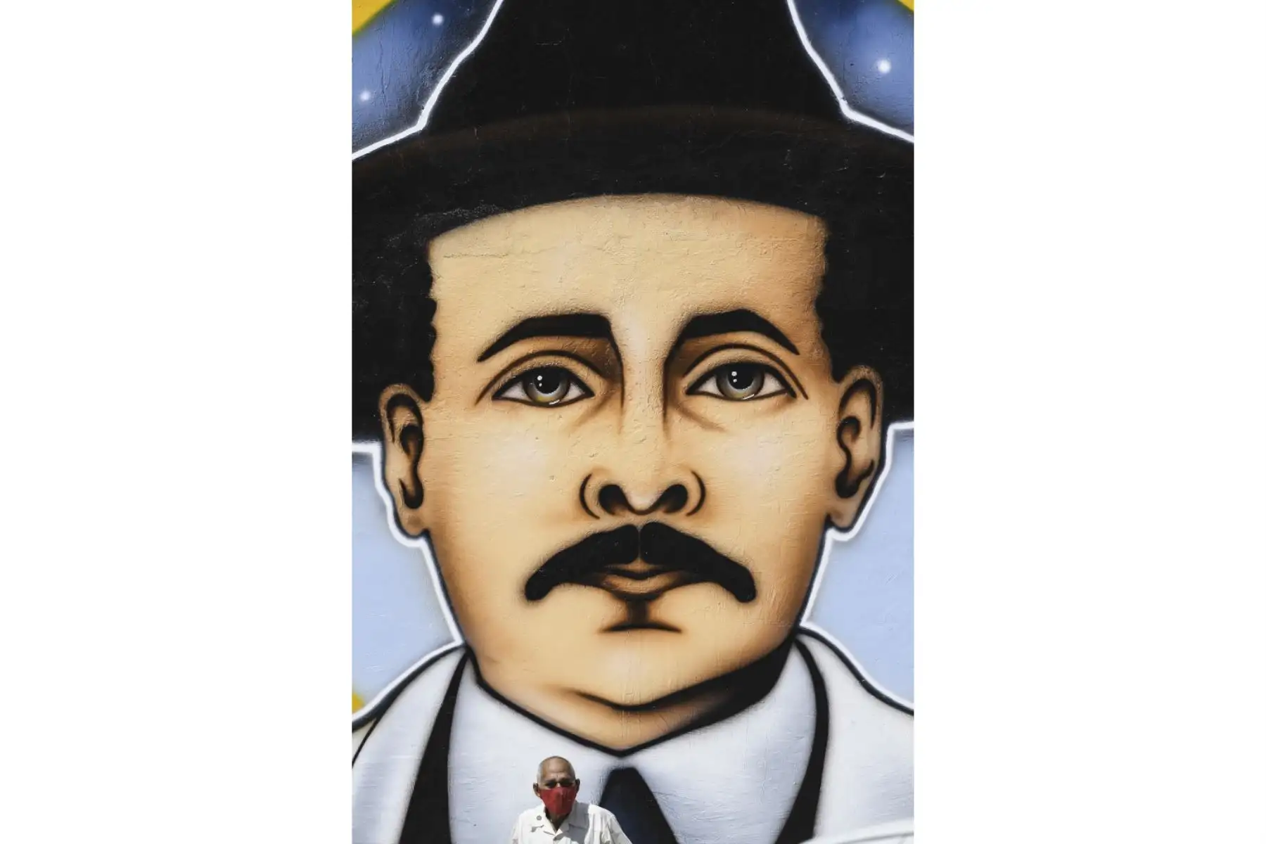 Un hombre parado junto a un mural que representa al médico venezolano José Gregorio Hernández, también llamado "el médico de los pobres", en una calle del barrio La Pastora -donde vivía- en Caracas el 30 de abril de 2021. Foto: AFP