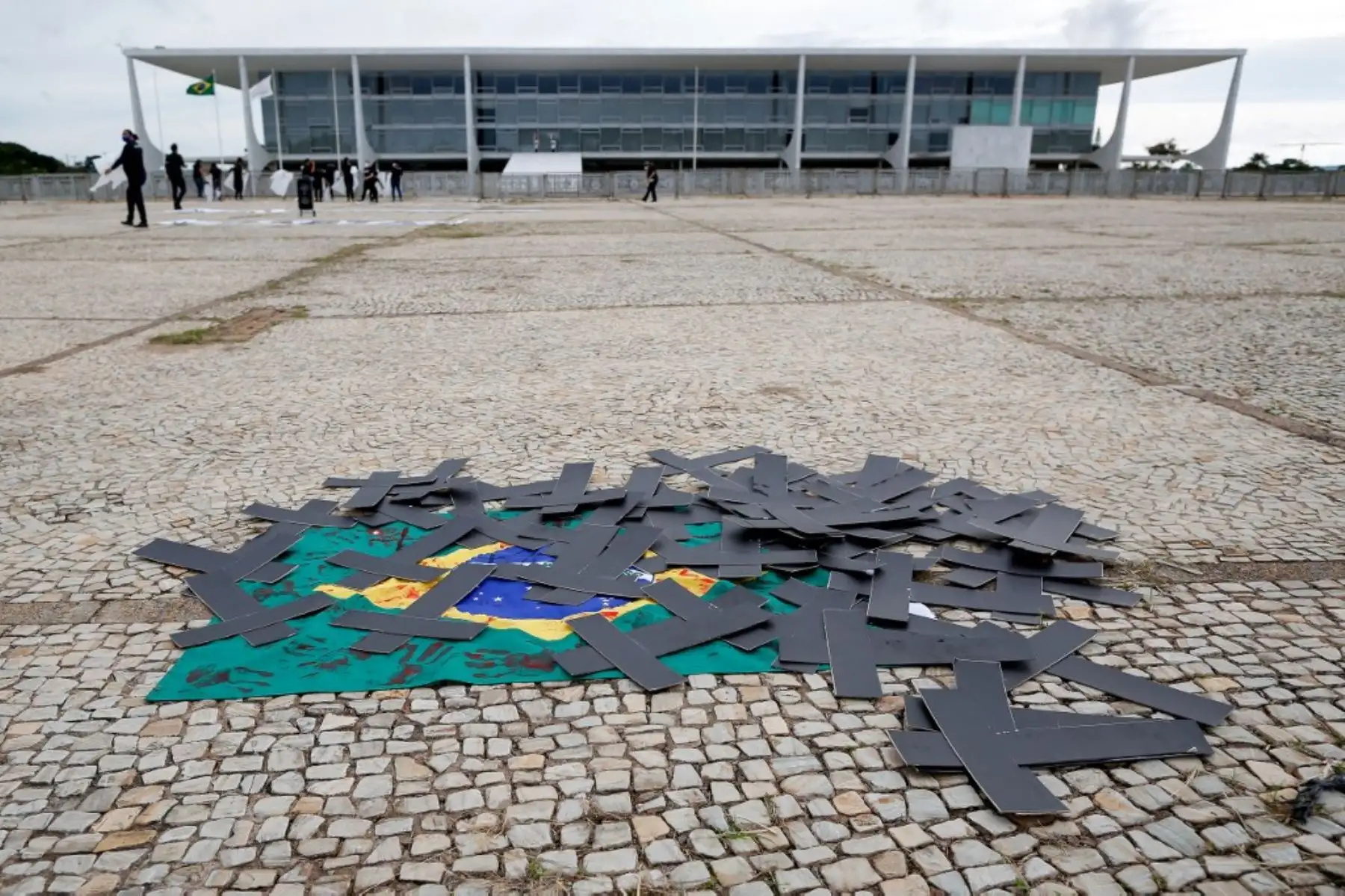 Cruces negras y una bandera brasileña manchada con tinta roja se ven durante una manifestación de enfermeras para protestar contra el presidente brasileño Jair Bolsonaro y rendir homenaje a los trabajadores de la salud que murieron por complicaciones del nuevo coronavirus covid-19, frente al Palacio Planalto en Brasilia. Foto: AFP