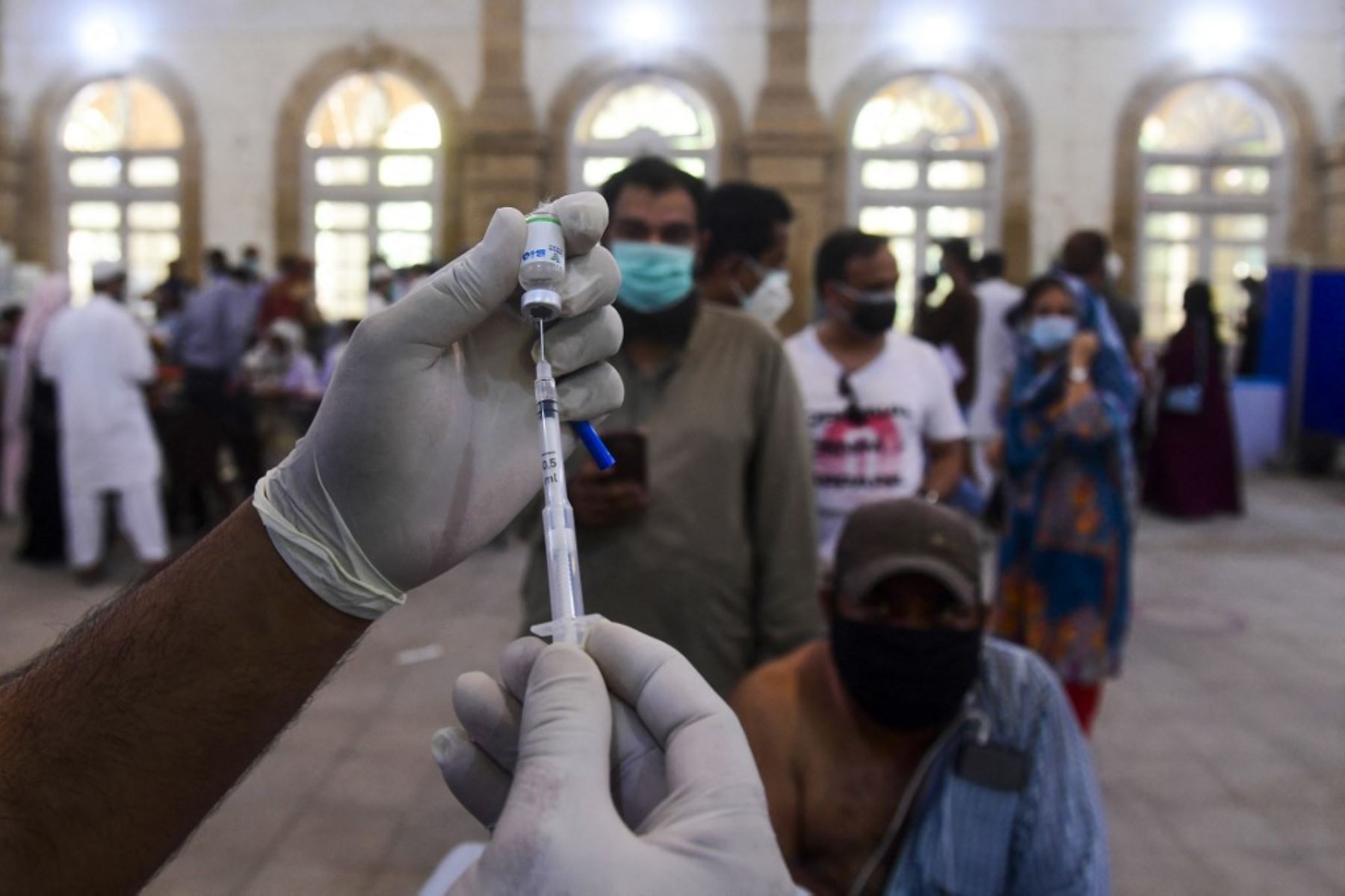 Un trabajador de la salud se prepara para inculcar a un hombre una dosis de la vacuna contra el coronavirus Sinopharm covid-19 en un centro de vacunación en Karachi. Foto: AFP