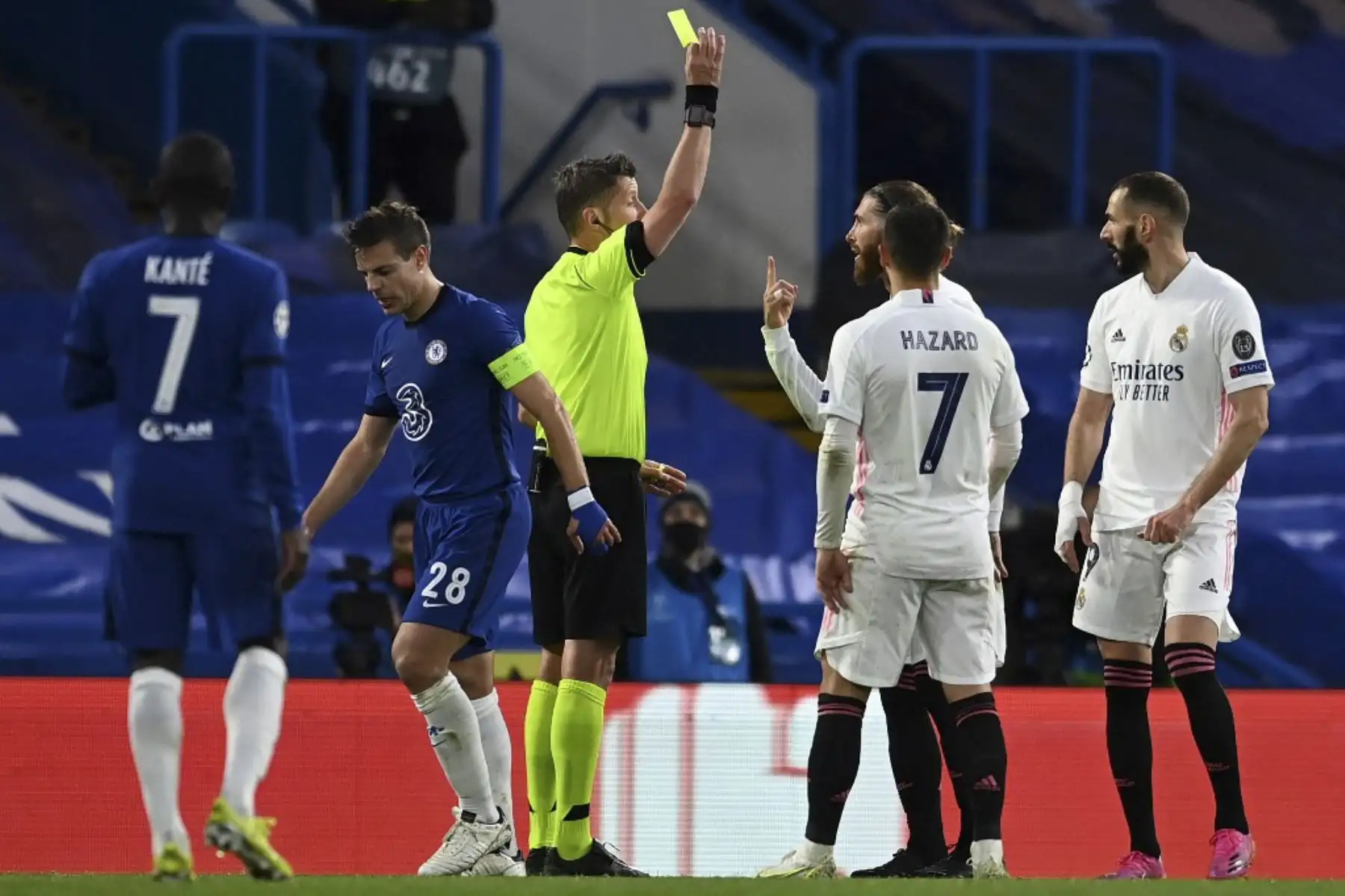 El árbitro italiano Daniele Orsato muestra una tarjeta amarilla al defensor español del Real Madrid Sergio Ramos por su falta sobre el defensor español del Chelsea César Azpilicueta durante el segundo tramo de la Liga de Campeones de la UEFA semifinal del partido de fútbol entre el Chelsea y el Real Madrid en Stamford Bridge en Londres. Foto: AFP