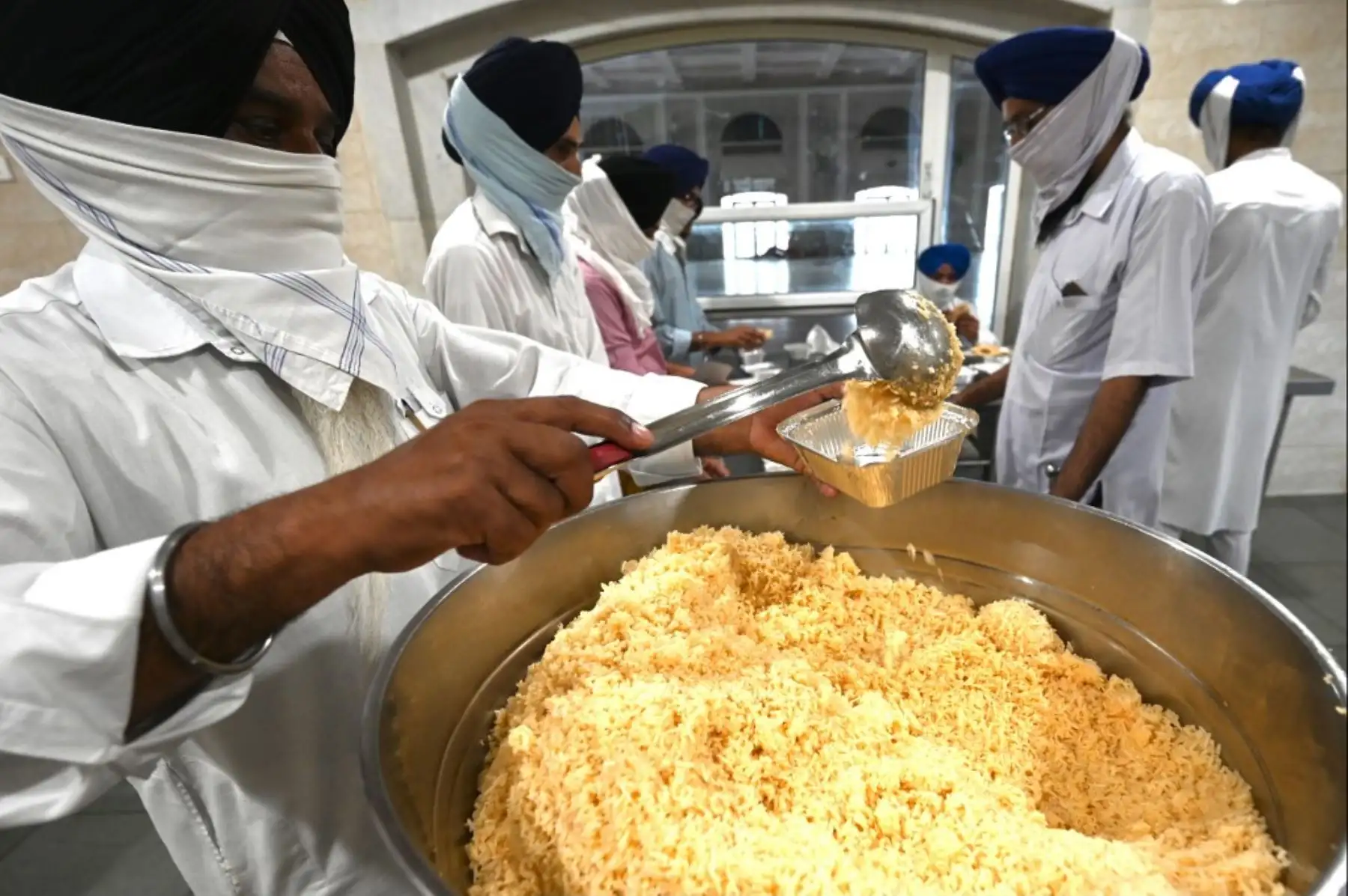 Voluntarios en un Gurudwara (templo sikh) empacan alimentos para pacientes con coronavirus covid-19 aislados en su casa, en la cocina comunitaria de Gurudwara en Nueva Delhi. Foto: AFP