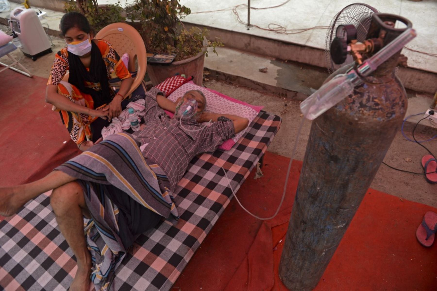 Un paciente respira con la ayuda de oxígeno provisto por un Gurudwara, un lugar de culto para los sijs, debajo de una carpa instalada a lo largo de la carretera en medio de la pandemia del coronavirus covid-19 en las afueras de Nueva Delhi. Foto: AFP