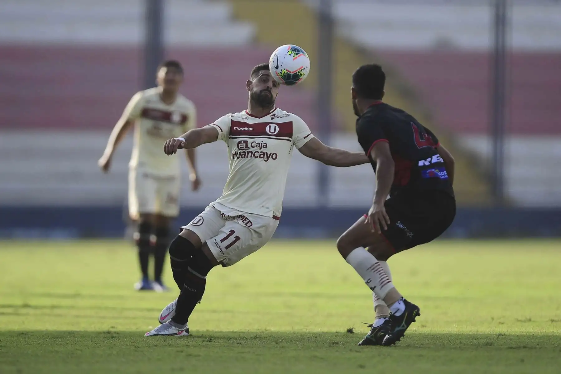 L. Urruti de Universitario lucha por el balón ante la marca de su rival de UTC durante partido por la fecha 3 de la Liga 1, en el estadio Iván Elías Moreno. Foto: Liga 1