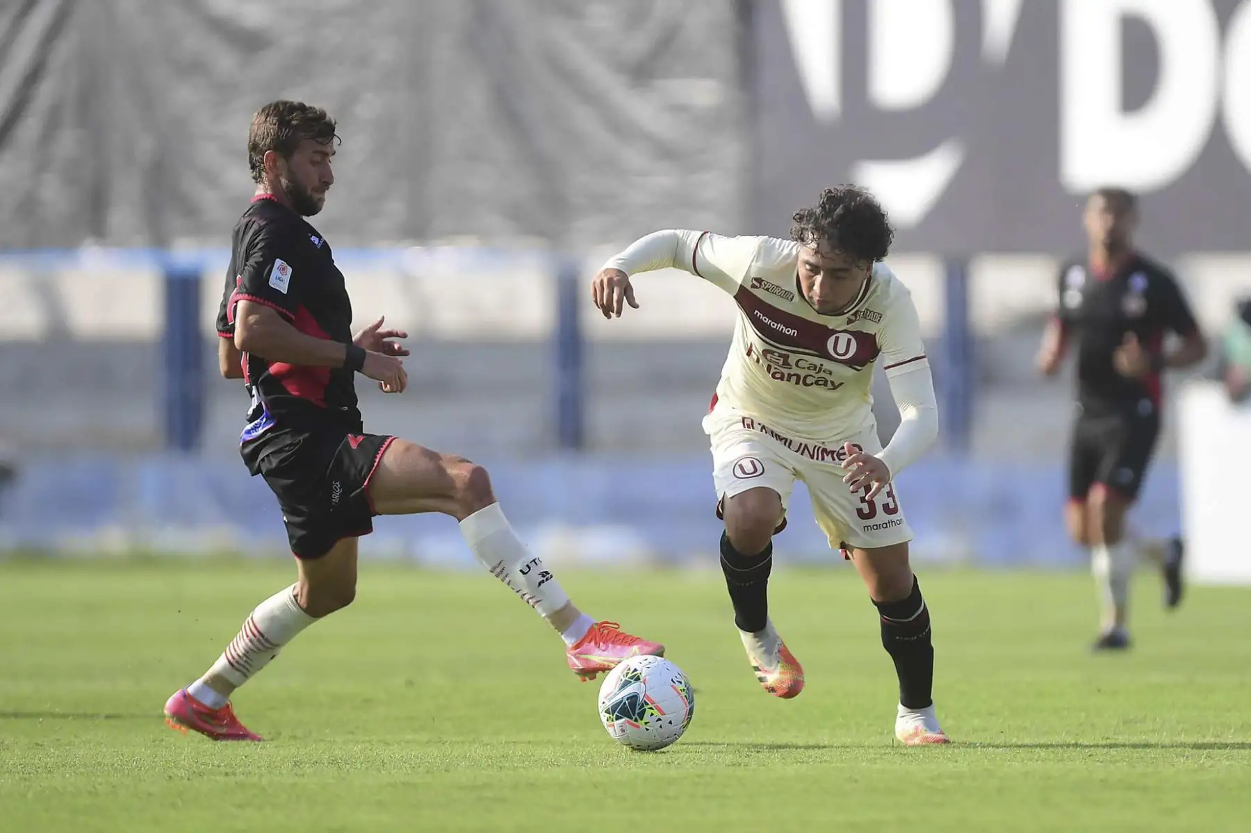 C. Flores de Universitario lucha por el balón ante la marca de su rival de UTC durante partido por la fecha 3 de la Liga 1, en el estadio Iván Elías Moreno. Foto: Liga 1