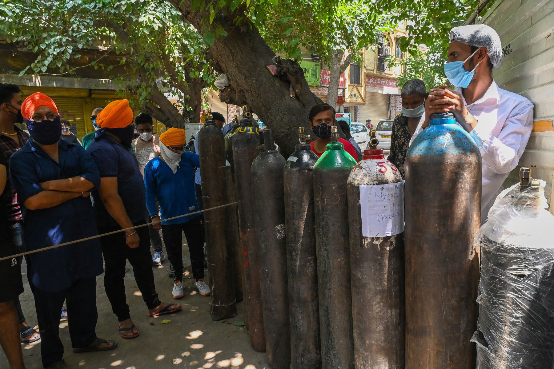 La gente espera para rellenar sus cilindros de oxígeno médico para los pacientes con Covid-19 bajo cuarentena domiciliaria en un centro de recarga privado, en Nueva Delhi, el 7 de mayo de 2021. Foto: AFP