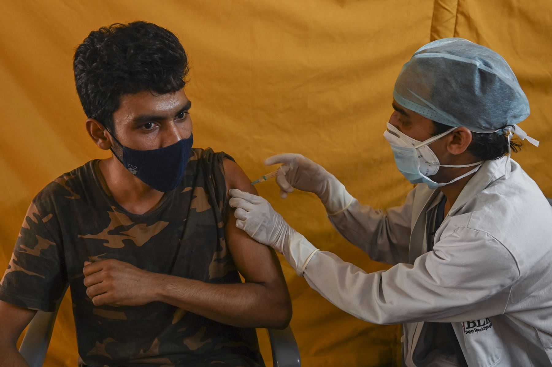 Un trabajador de la salud inocula a un hombre con una dosis de la vacuna contra el coronavirus Covishield Covid-19 en un centro de Nueva Delhi, el 6 de mayo de 2021. Foto: AFP