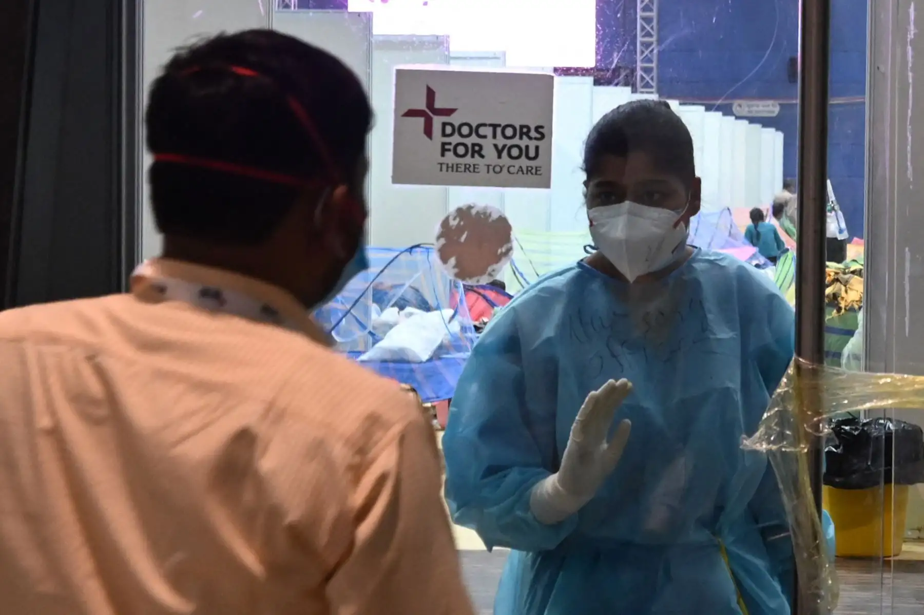 Un trabajador de la salud habla con un paciente Covid-19 dentro del estadio Common Wealth Games convertido temporalmente en el centro de atención, en Nueva Delhi, el 5 de mayo de 2021. Foto: AFP