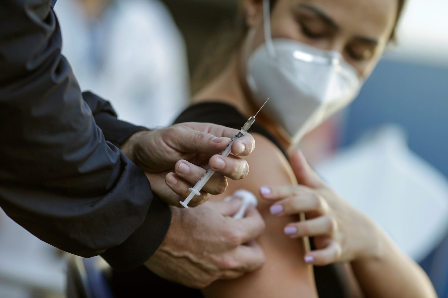 Una mujer que lleva una máscara protectora recibe una dosis de la vacuna de Pfizer/BioNTech contra la covid-19 este martes en la clínica familiar en Río de Janeiro, Brasil. Foto: EFE