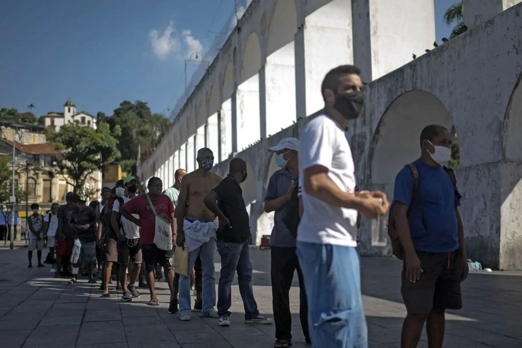 Hombres sin hogar hacen cola para recibir una comida de los miembros del proyecto Covid Sem Fome, en la atracción turística de renombre internacional de Los Arcos de Lapa, en el centro de Río de Janeiro, Brasil, el 05 de mayo de 2021. Foto: AFP