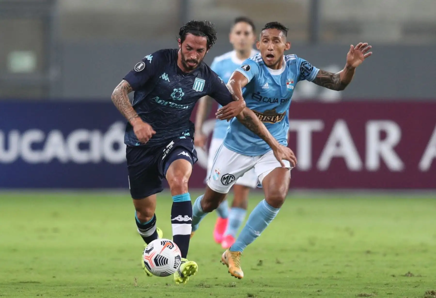 El jugador Christofer Gonzales del Sporting Cristal compiten por el balón, con Matías Schelotto de El Racing Club de Argentina, durante el partido de fútbol por lLa Copa Libertadores en el Estadio Nacional de Lima. Foto: AFP
