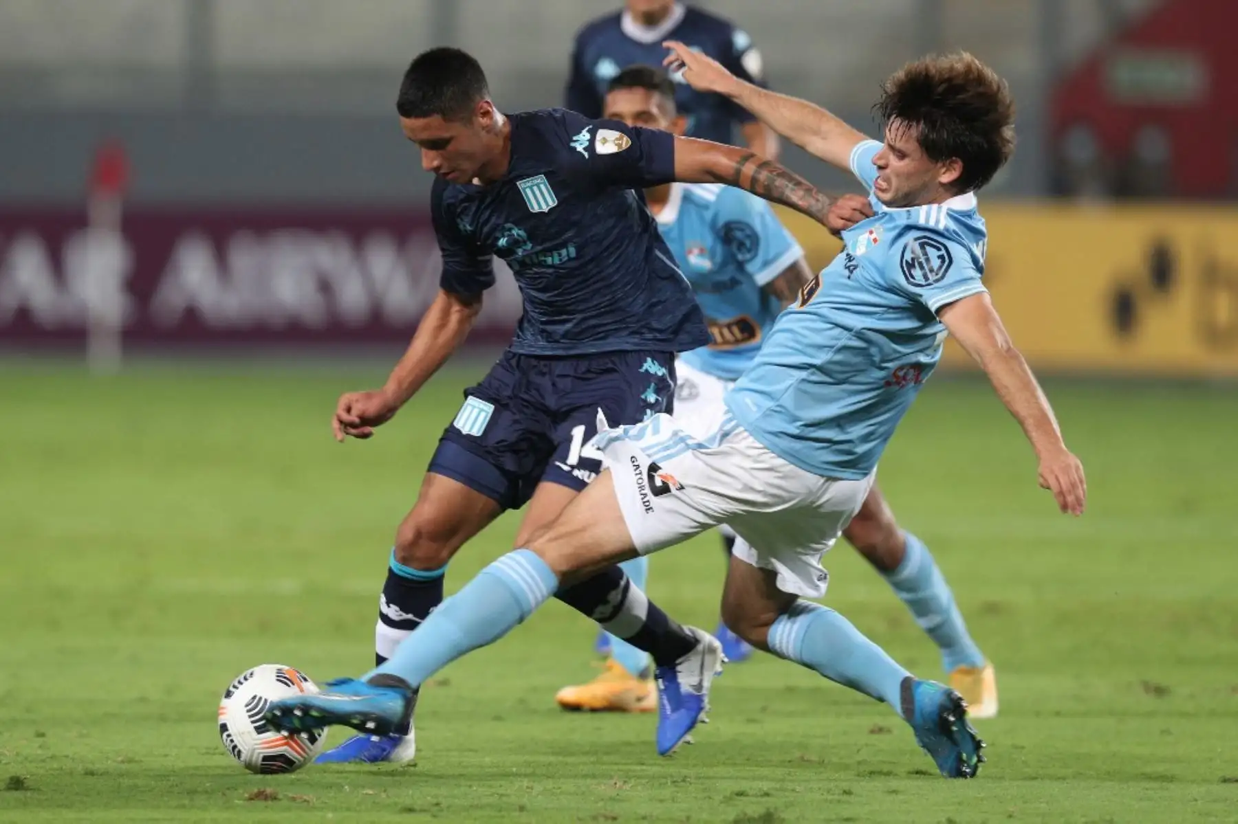 El jugador  Omar Merlo del Sporting Cristal compiten por el balón, con Santiago Godoy de El Racing Club de Argentina, durante el partido de fútbol por La Copa Libertadores en el Estadio Nacional de Lima. Foto: AFP