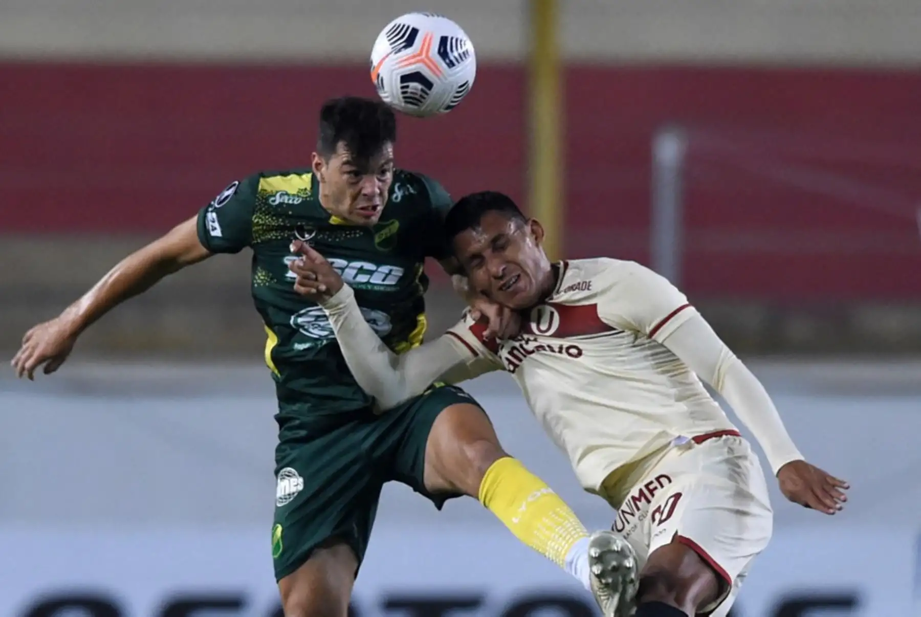 El jugador Fernando Meza del Defensa y Justicia y  el peruano Alex Valera de Universitario, compiten por el balón durante su partido de la fase de grupos del torneo de fútbol Copa Libertadores en el Estadio Ate Monumental en Lima. Foto: AFP